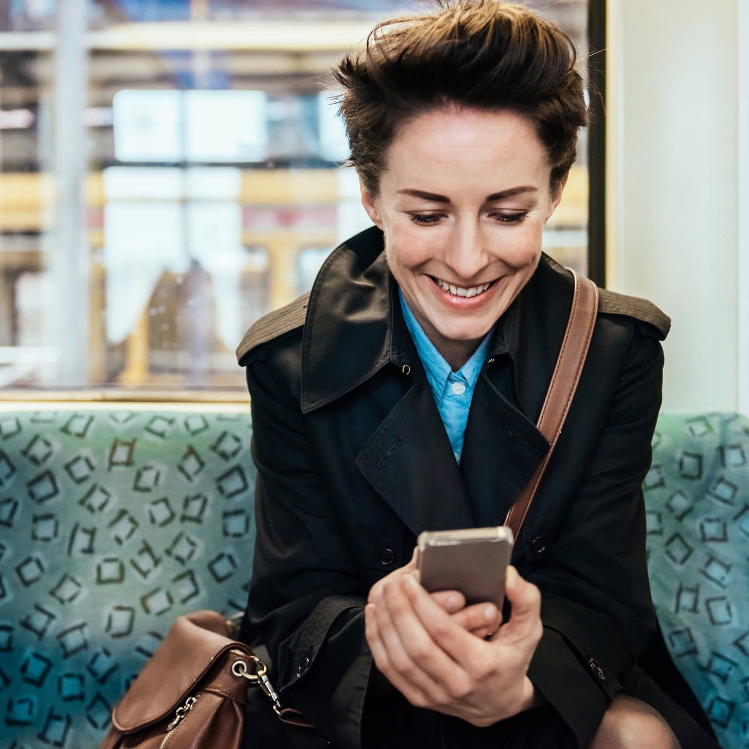 Image: Woman checking benfits of DAK on her smart phone while commuting in train.