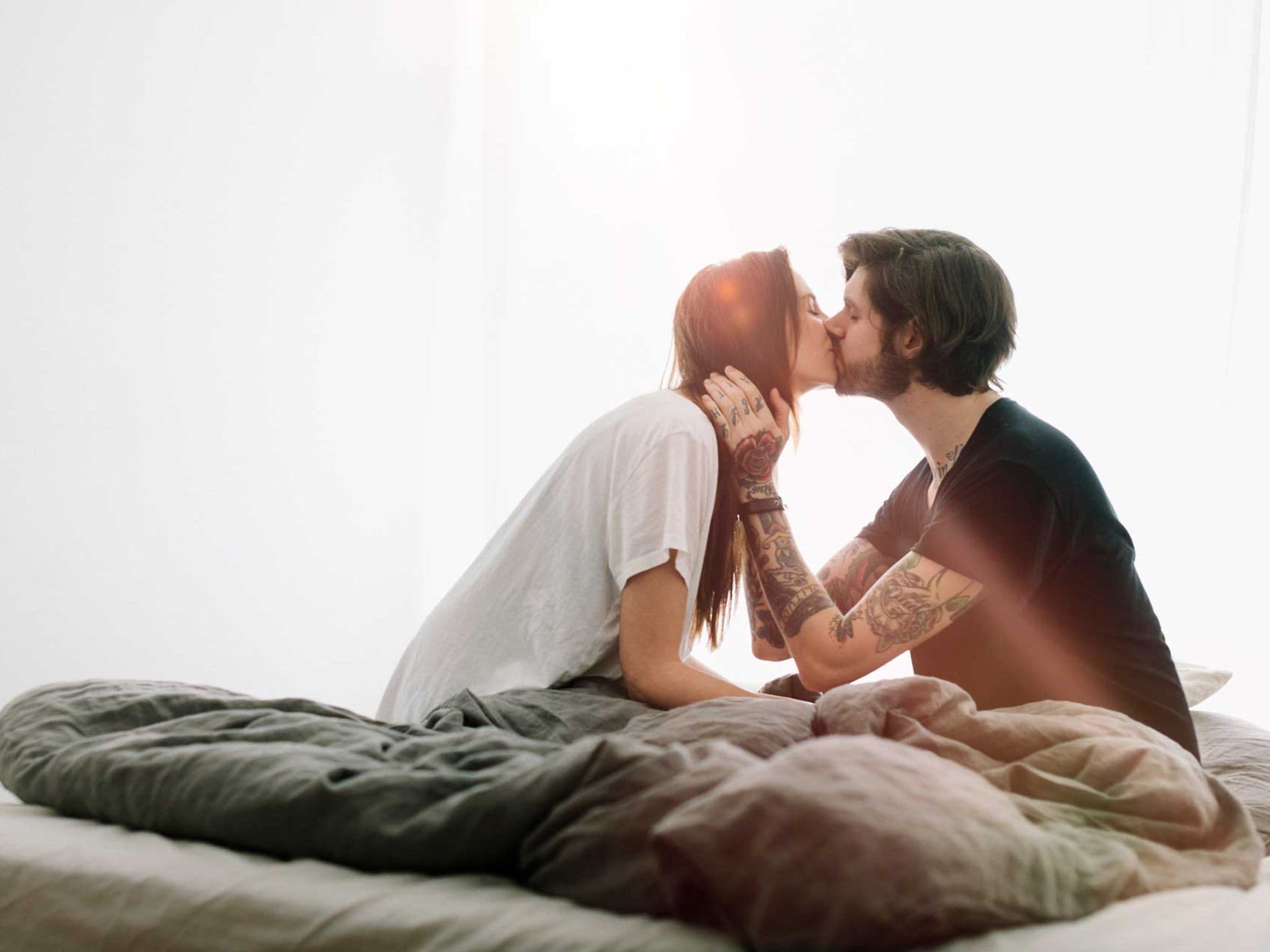 Symbolbild Pille danach: Junges Paar küsst sich im Bett