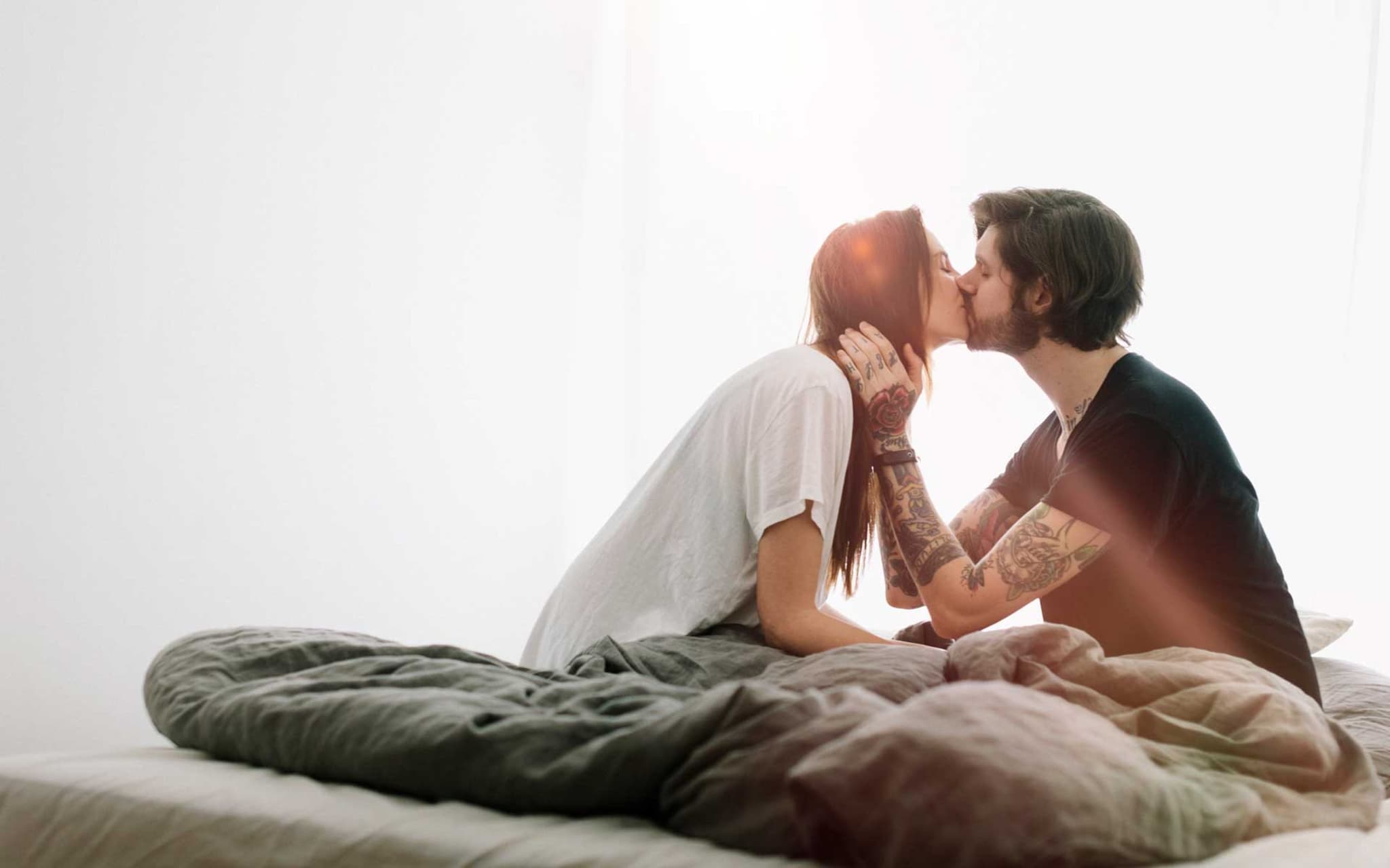 Symbolbild Pille danach: Junges Paar küsst sich im Bett