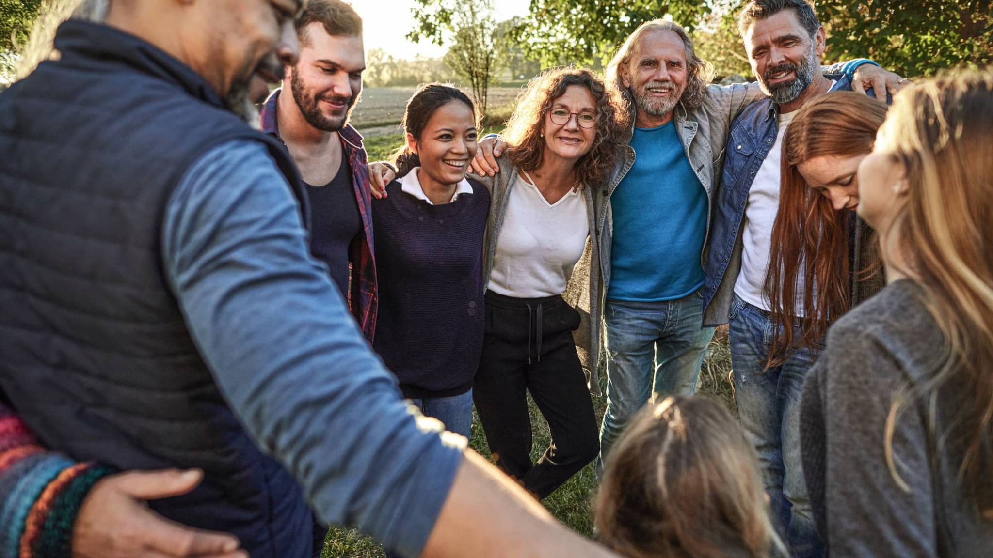 Bild: Internationale Personengruppe umarmt sich bei einem Sommerfest.