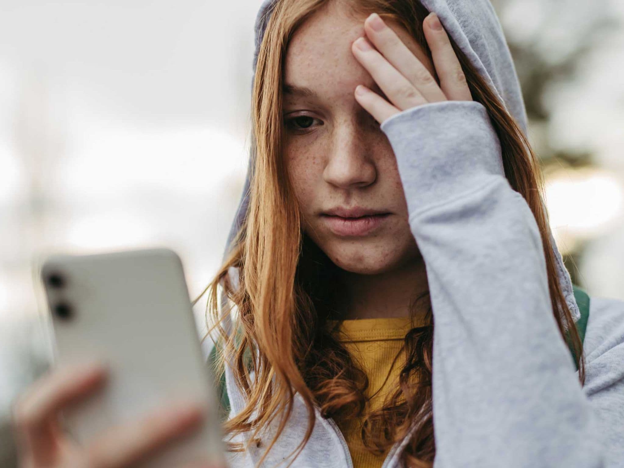Symbolbild Cybermobbing: Mädchen guckt besorgt auf ihr Smartphone