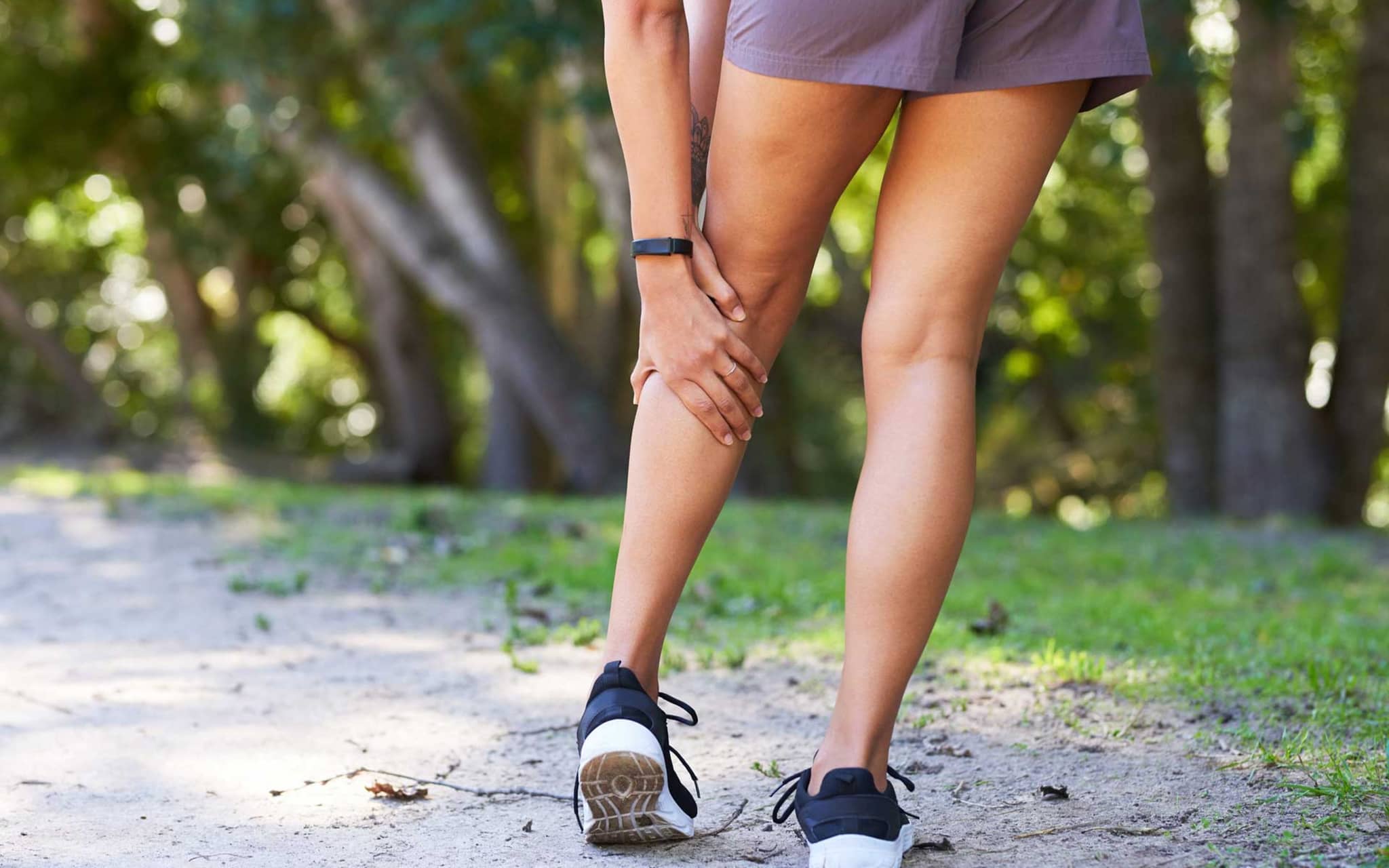 Symbolbild Muskelkrämpfe: Junge Frau fasst sich an Wade