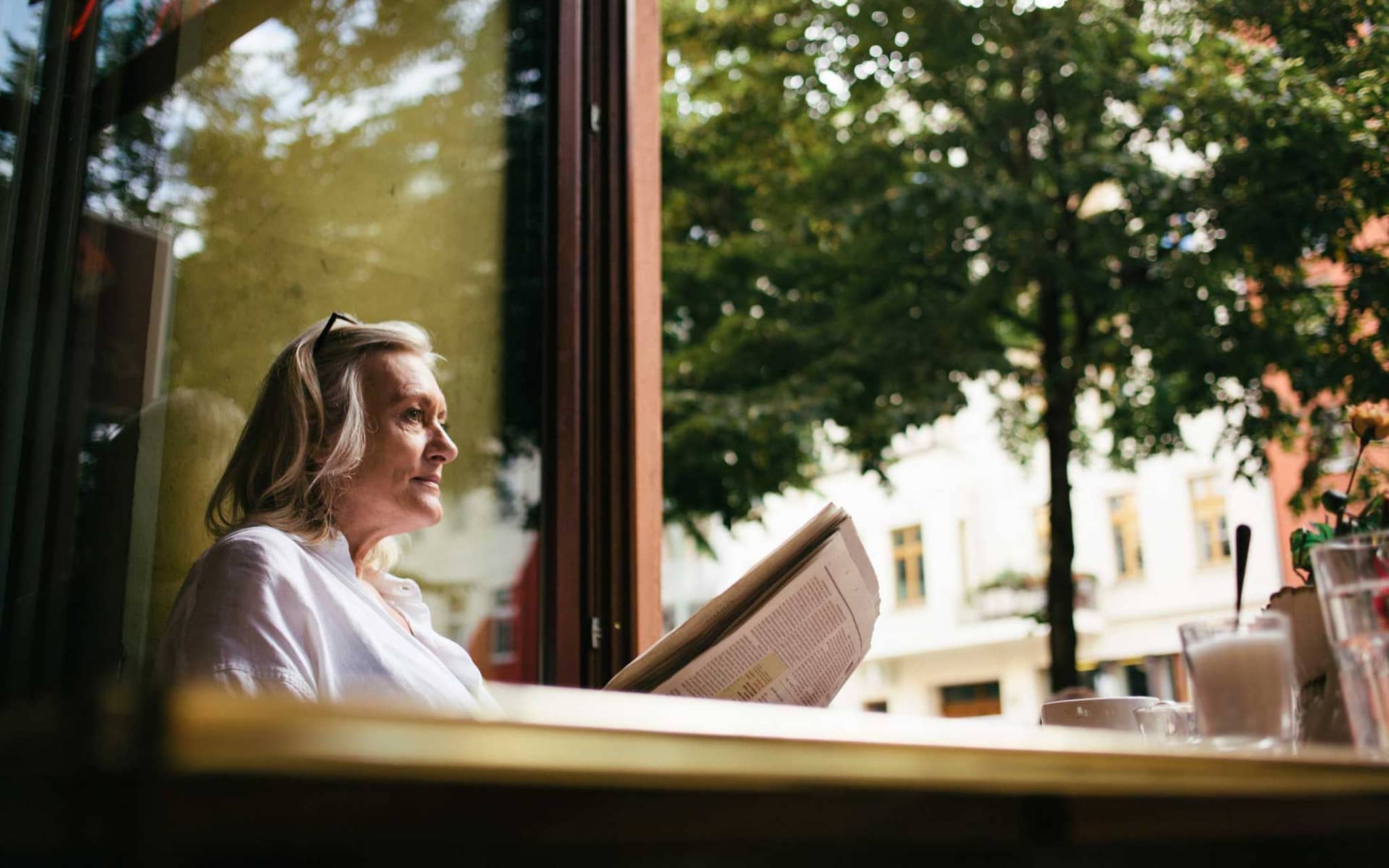 Symbolbild Exazerbation bei COPD: Frau sitzt allein in einem Café