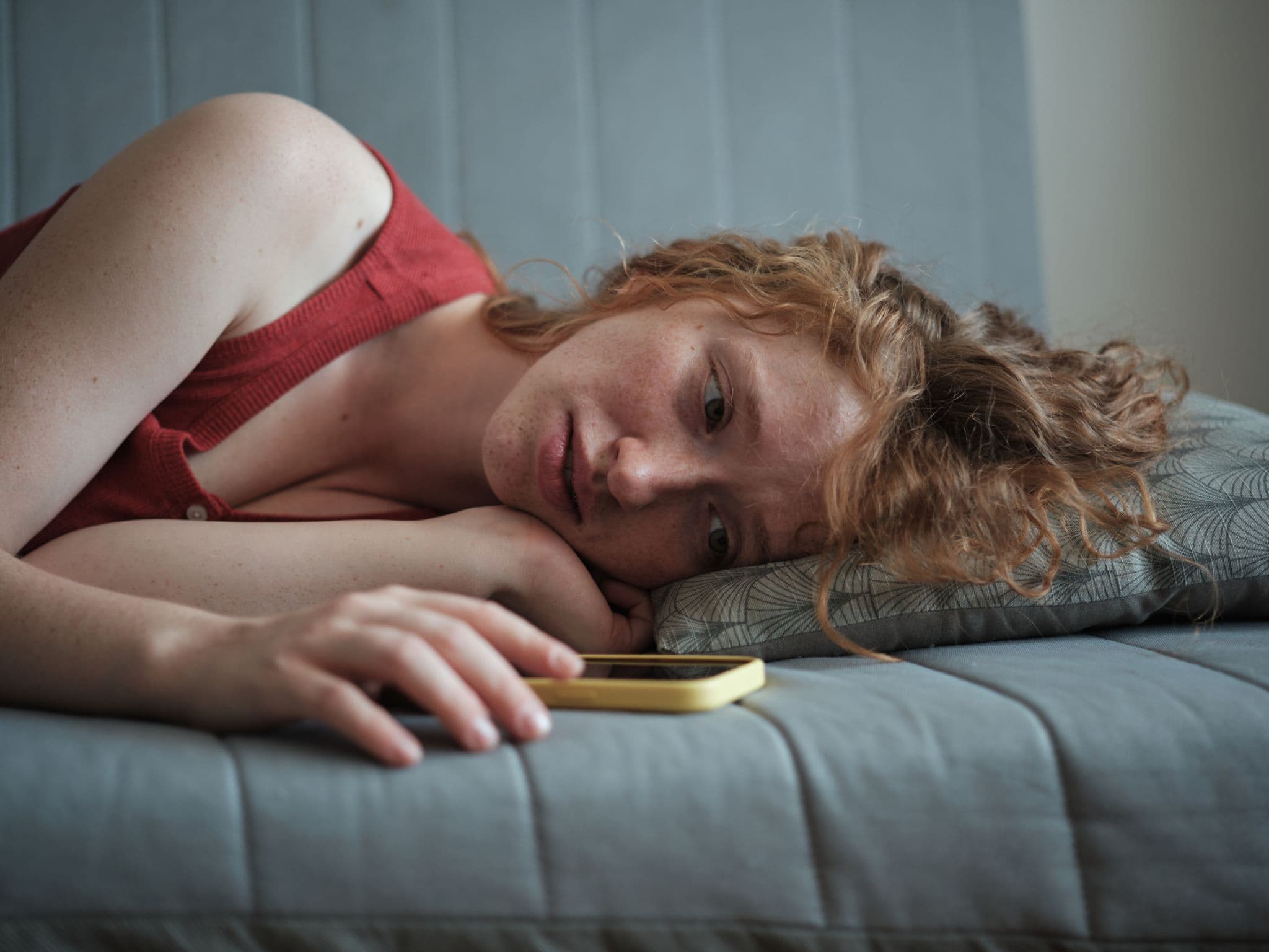 Symbolbild für Liebeskummer: Ein junges Mädchen schaut auf ihr Handy uns ist traurig