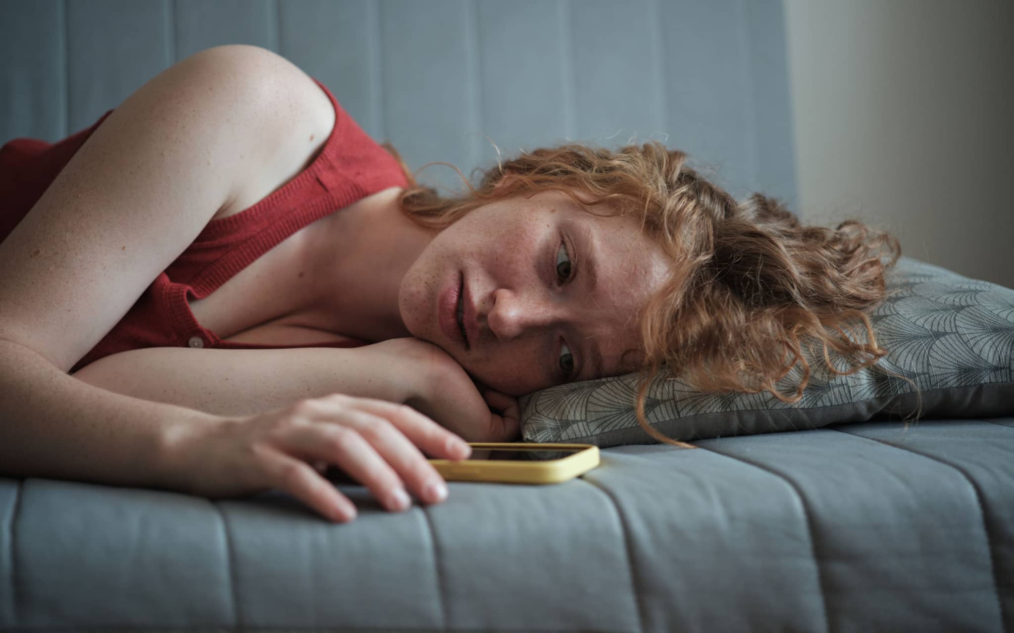 Symbolbild für Liebeskummer: Ein junges Mädchen schaut auf ihr Handy uns ist traurig