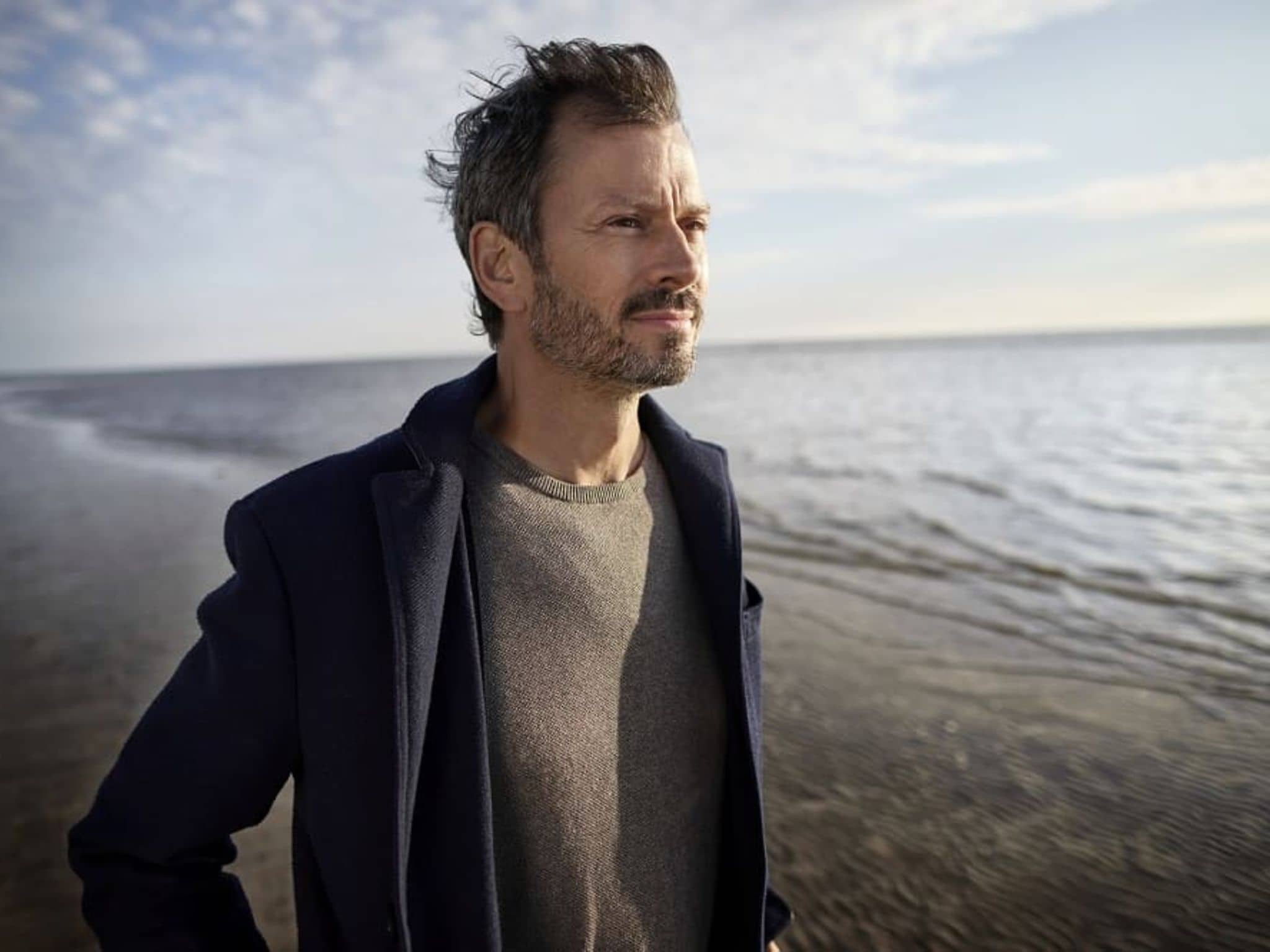 Midlife-Crisis: Reiferer Mann in der Krise geht gedankenverloren am Strand spazieren.