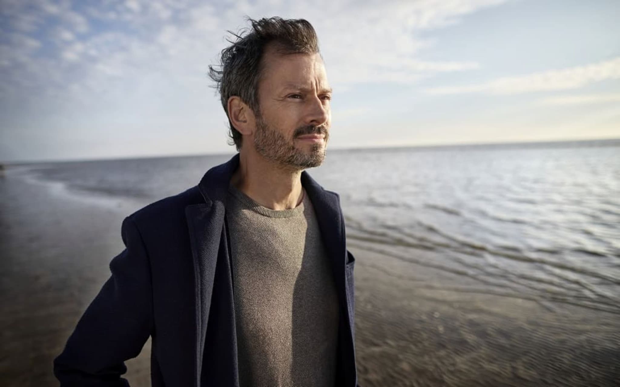 Midlife-Crisis: Reiferer Mann in der Krise geht gedankenverloren am Strand spazieren.