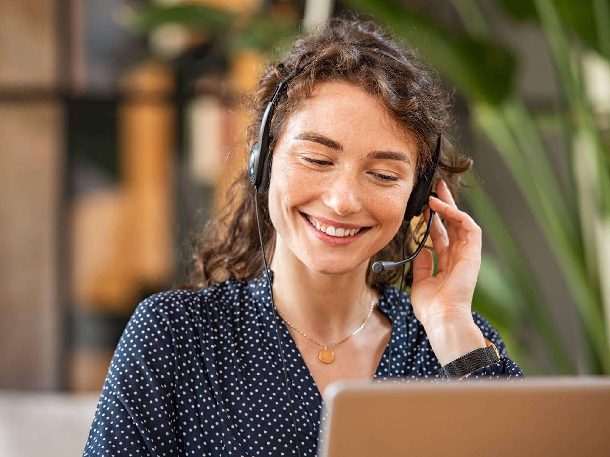 Bild: Junge Frau mit Locken und Headset telefoniert.