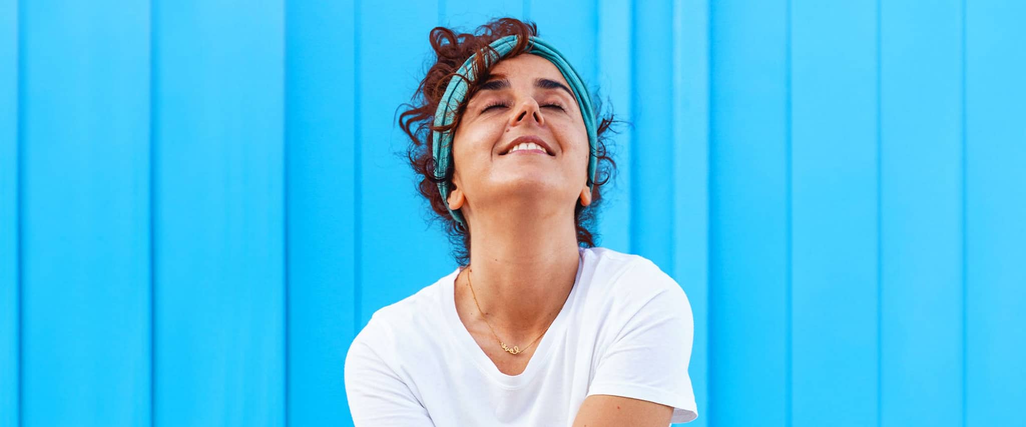 DAK Wahltarife: Junge Frau steht vor einer blauen Wand.