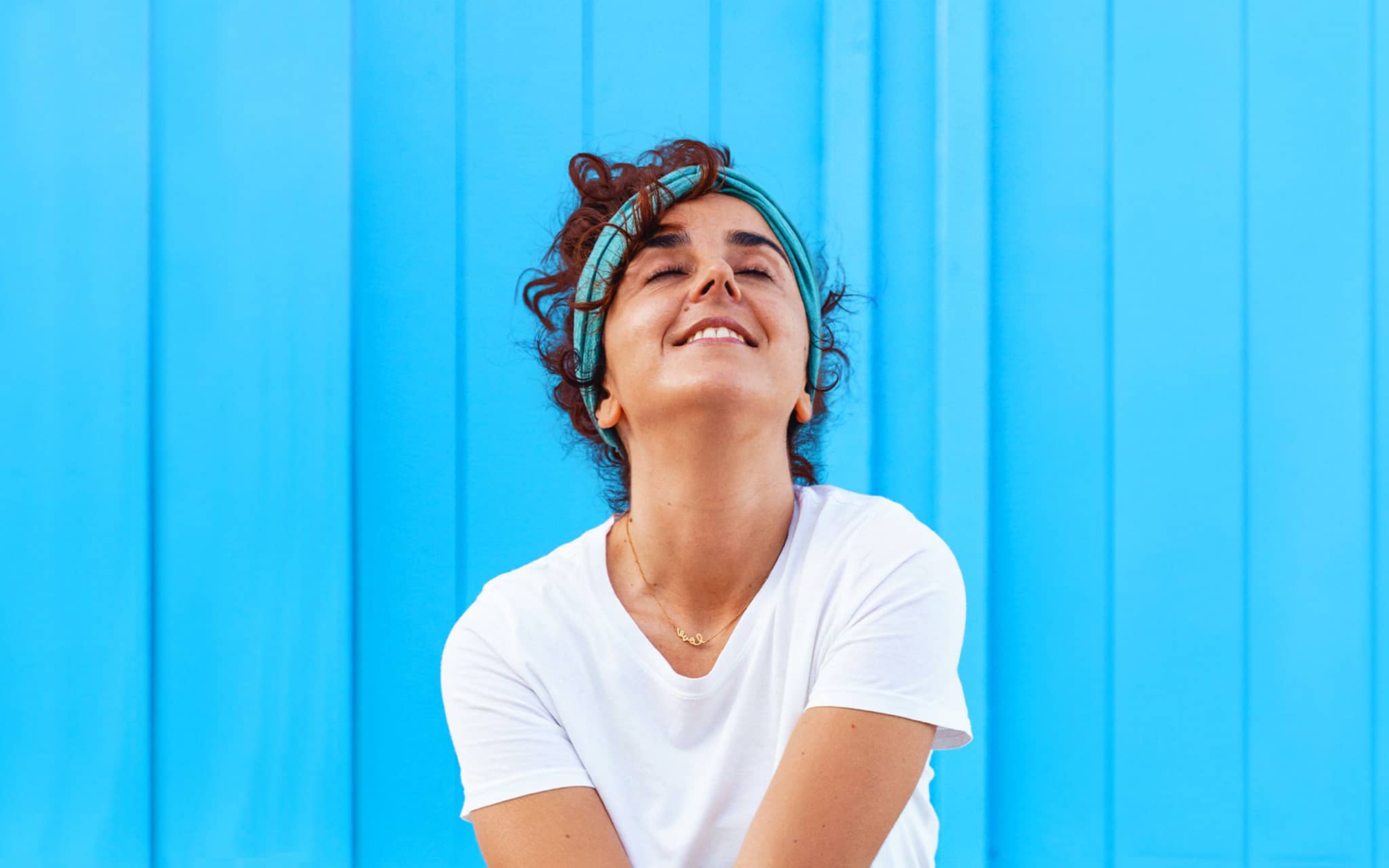 DAK Wahltarife: Junge Frau steht vor einer blauen Wand.