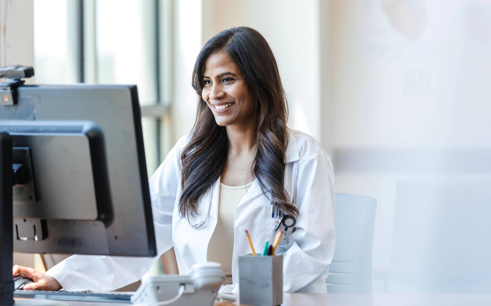 Bild: Ärztin sitzt am Computer und stellt ein E-Rezept aus.