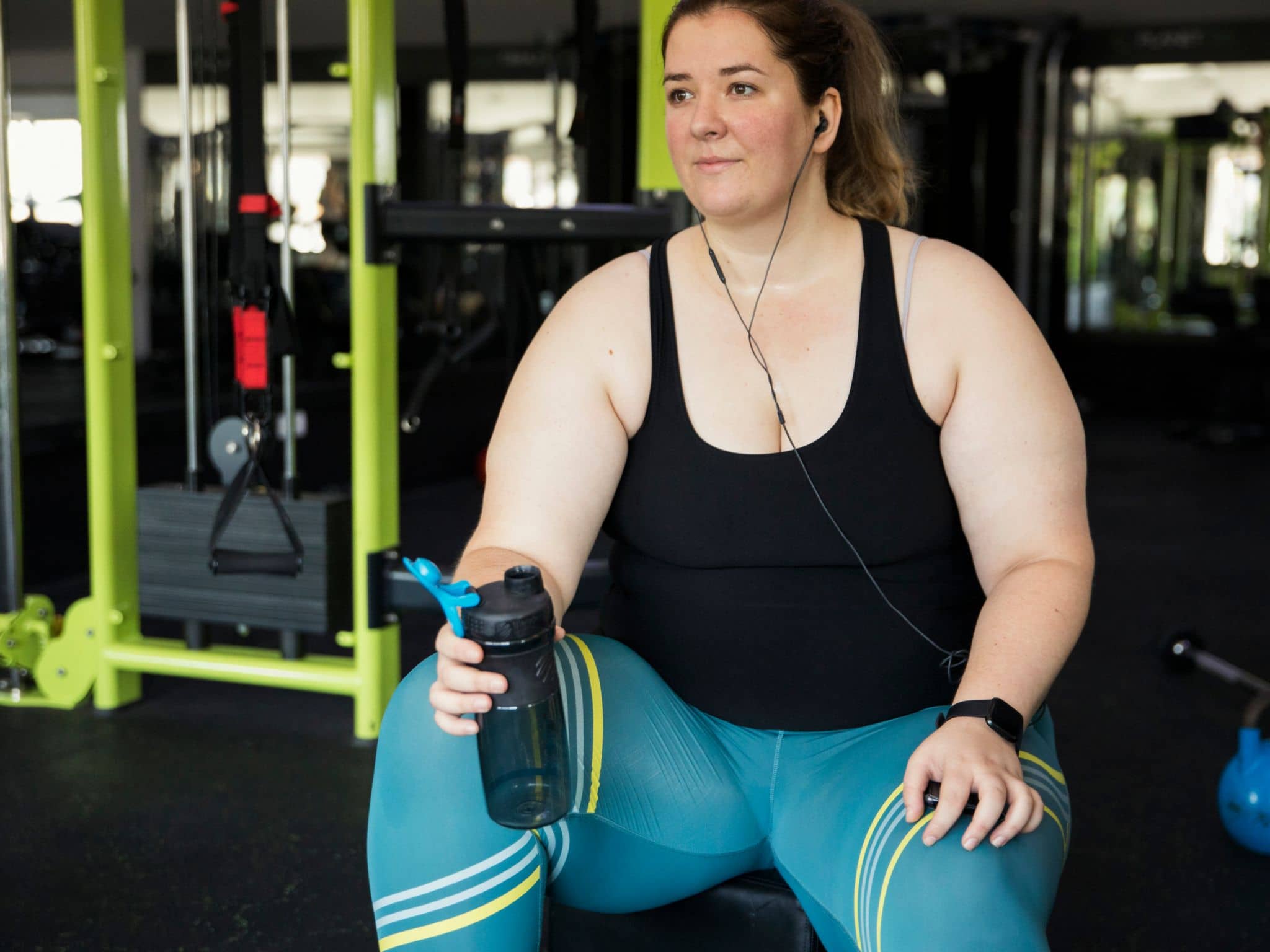 Sport bei Adipositas: Eine junge, übergewichtige Frau trainiert im Fitnessstudio