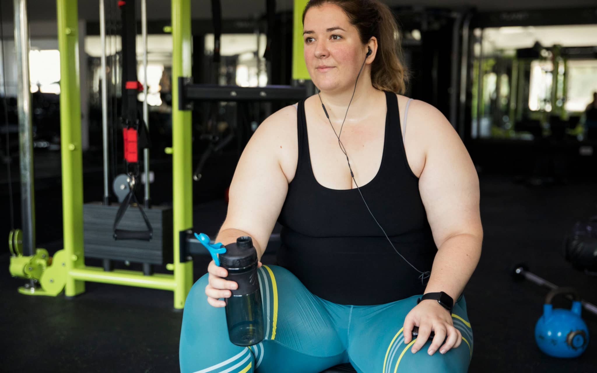 Sport bei Adipositas: Eine junge, übergewichtige Frau trainiert im Fitnessstudio