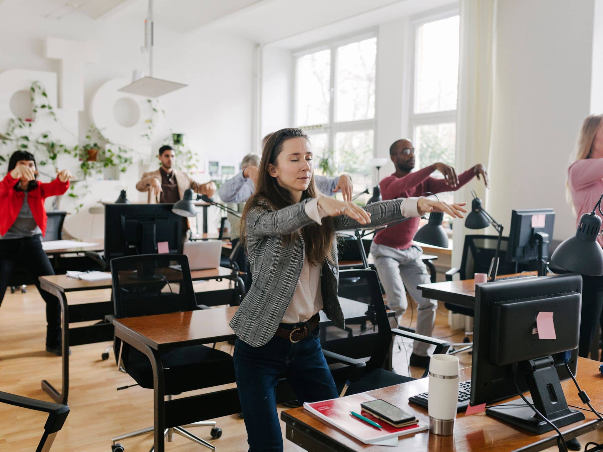 Menschen im Großraumbüro machen gemeinsam eine Bewegungspause.
