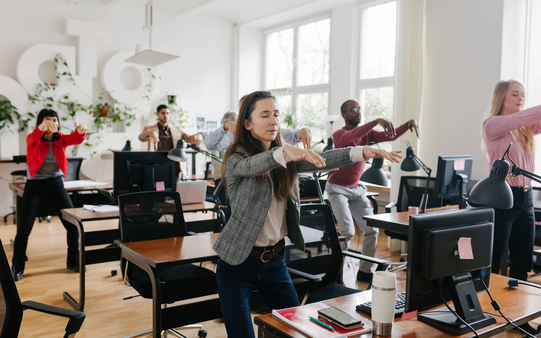 Menschen im Großraumbüro machen gemeinsam eine Bewegungspause.