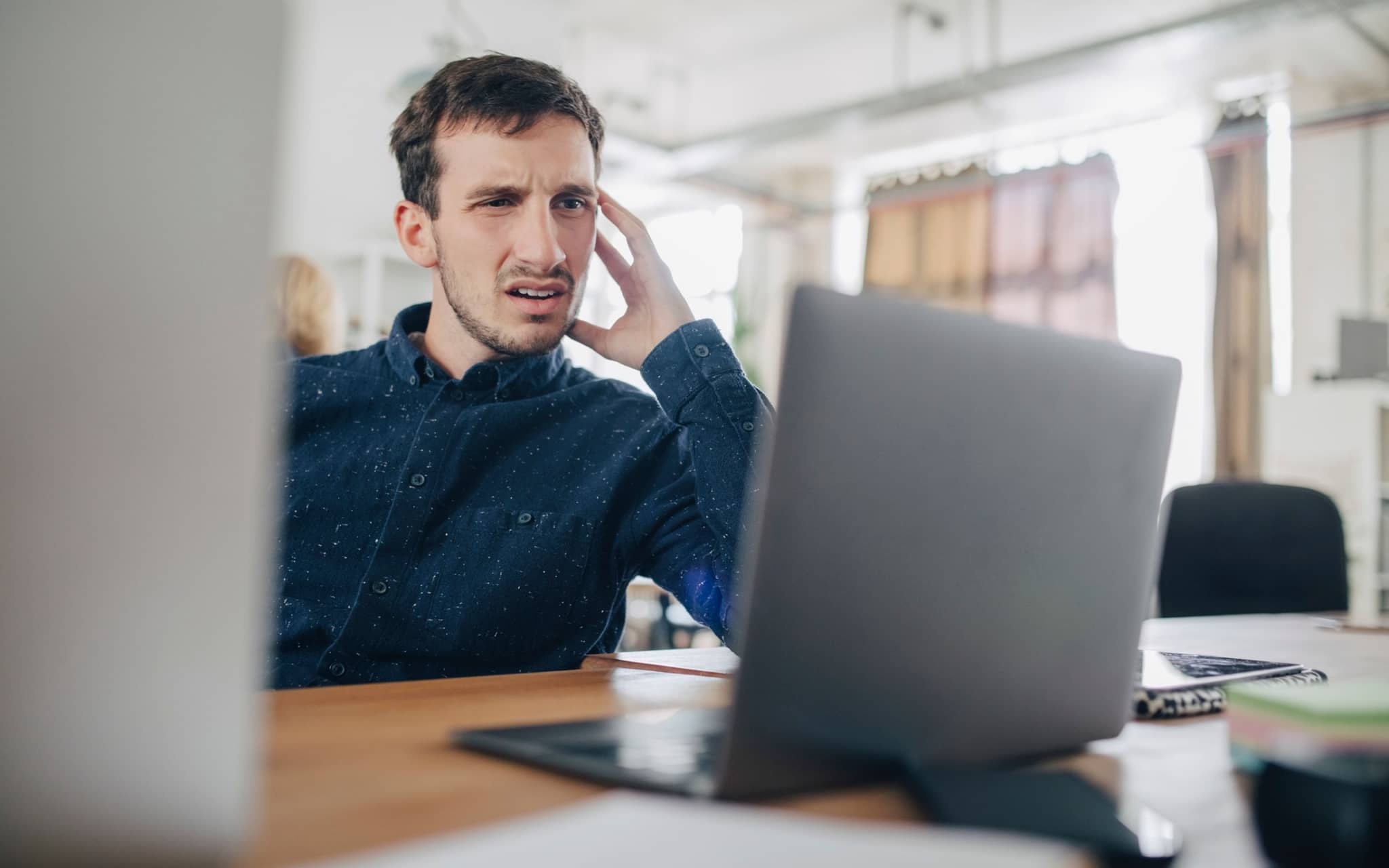 Mann sitzt vor dem Laptop und guckt irritiert.
