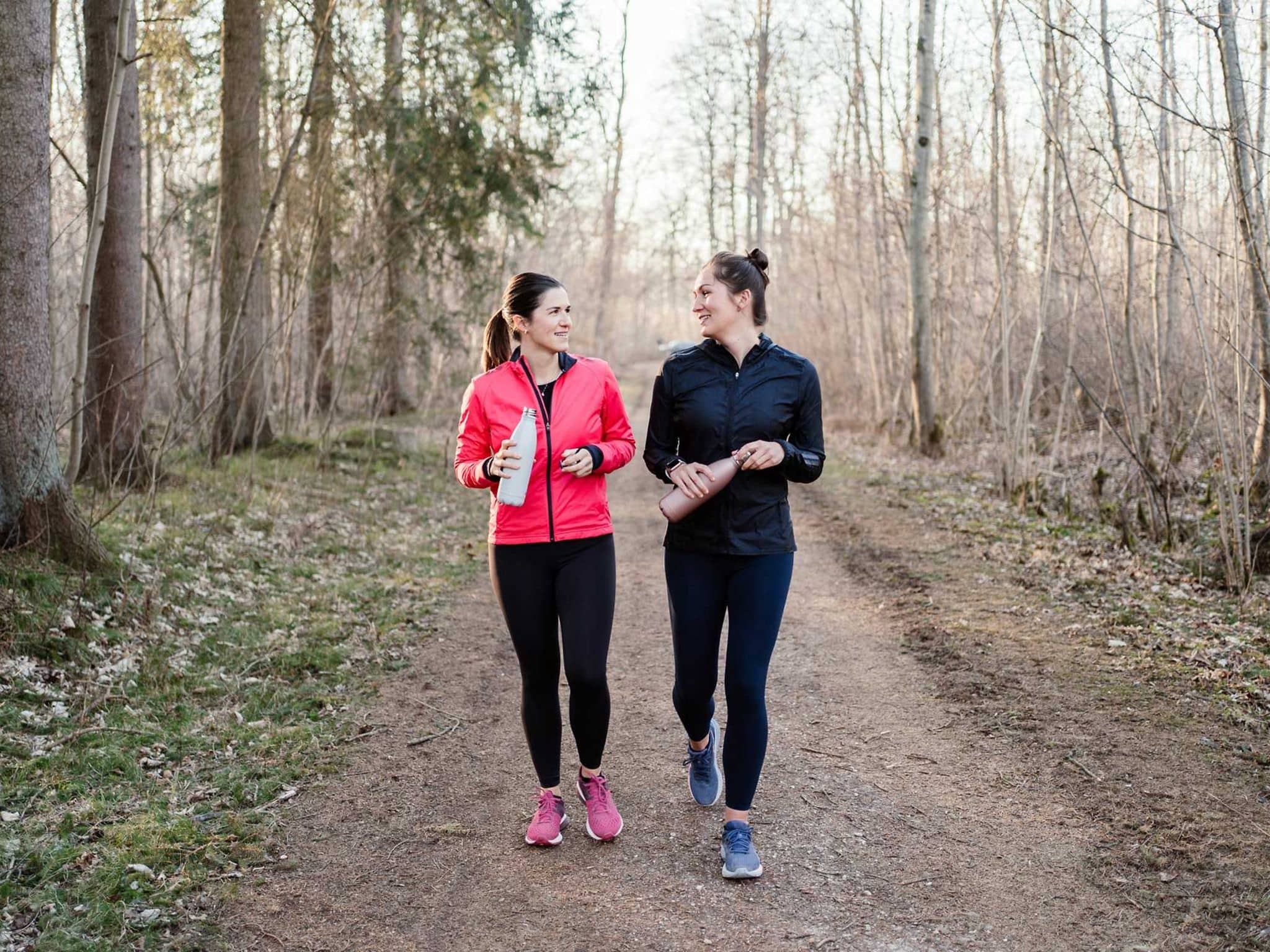 Sport für Anfänger: Zwei Frauen walken im blätterlosen Wald.