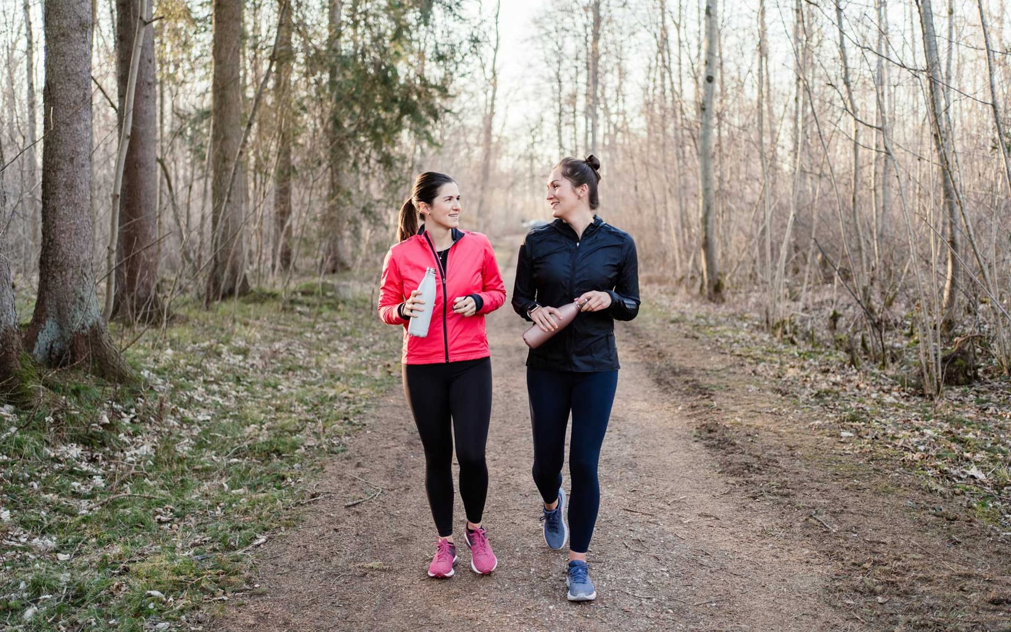 Sport für Anfänger: Zwei Frauen walken im blätterlosen Wald.