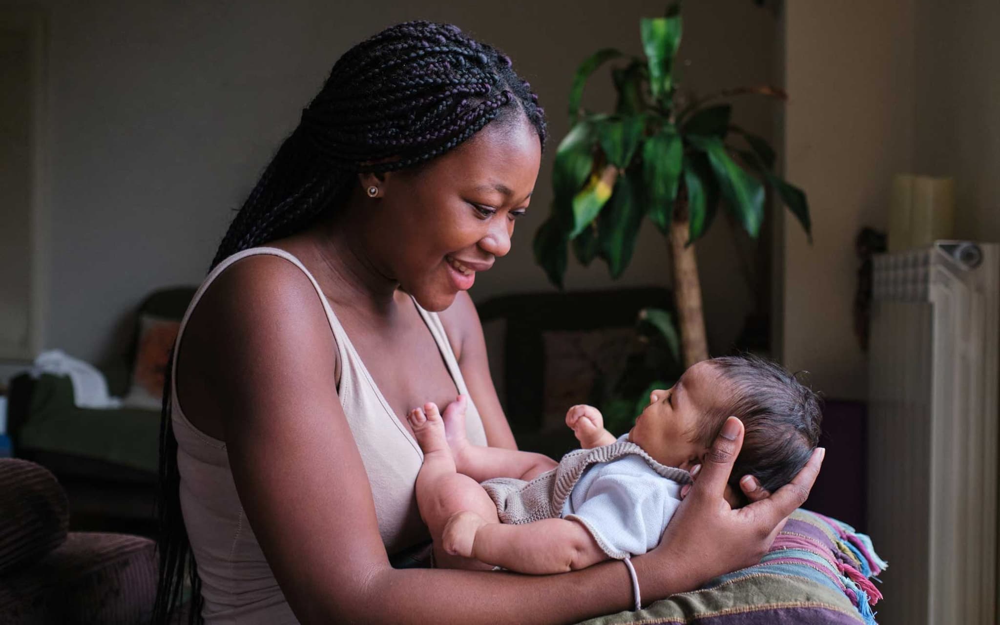 Schwarze Frau hält ihr Neugeborenes nach dem Stillen im Arm