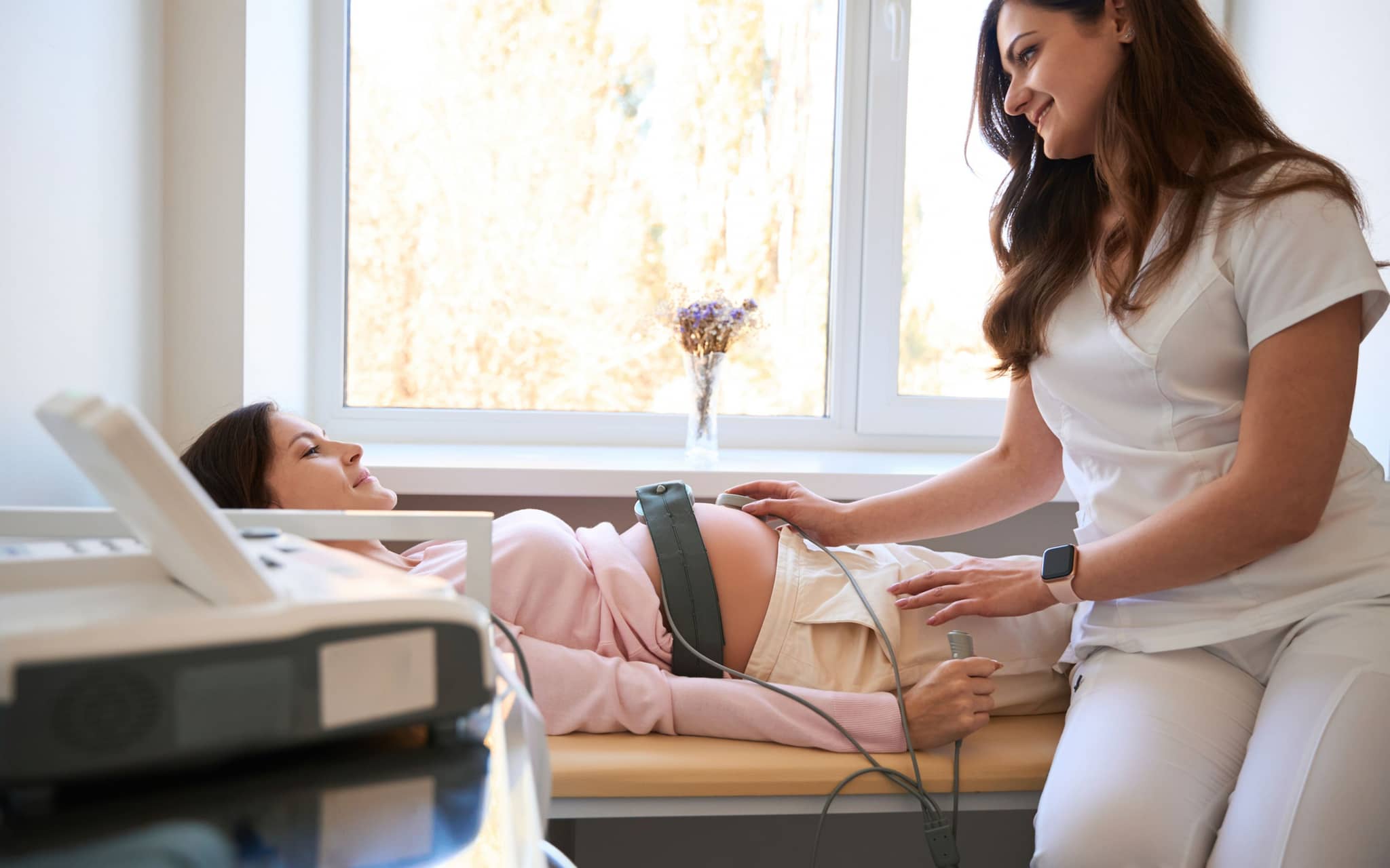 CTG-Wehenschreiber: Eine Schwangere liegt auf einer Liege und bekommt ein CTG