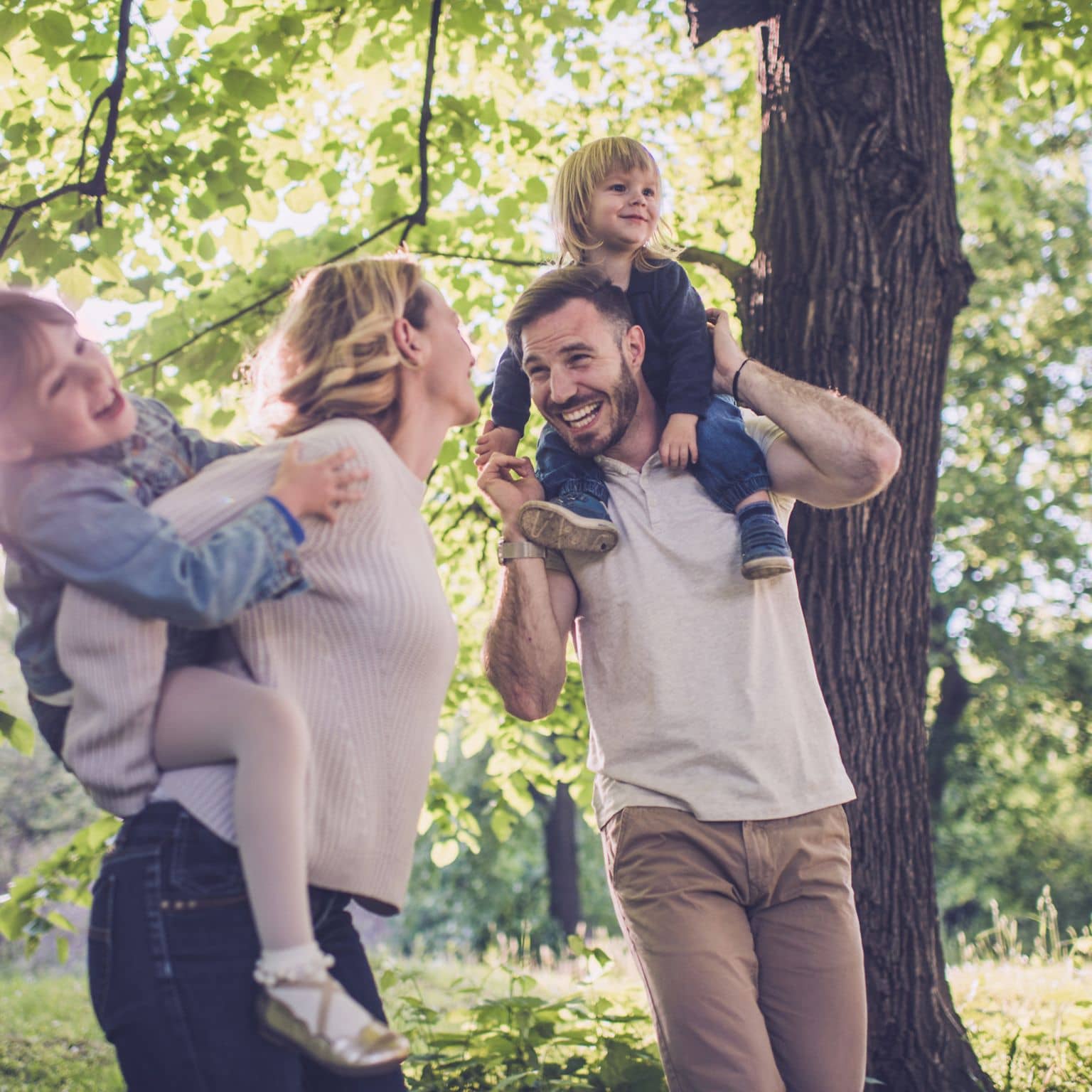Klimaschutz und Nachhaltigkeit: Lachendes Paar mit zwei kleinen Kindern in der Natur.