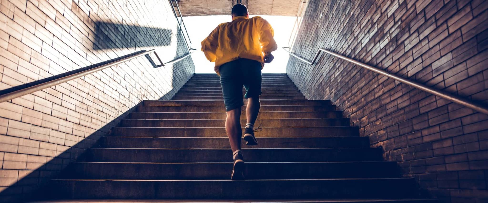 Bonuspunkte sammeln durch Sport: Junger Mann läuft Treppen im Tunnel hoch.