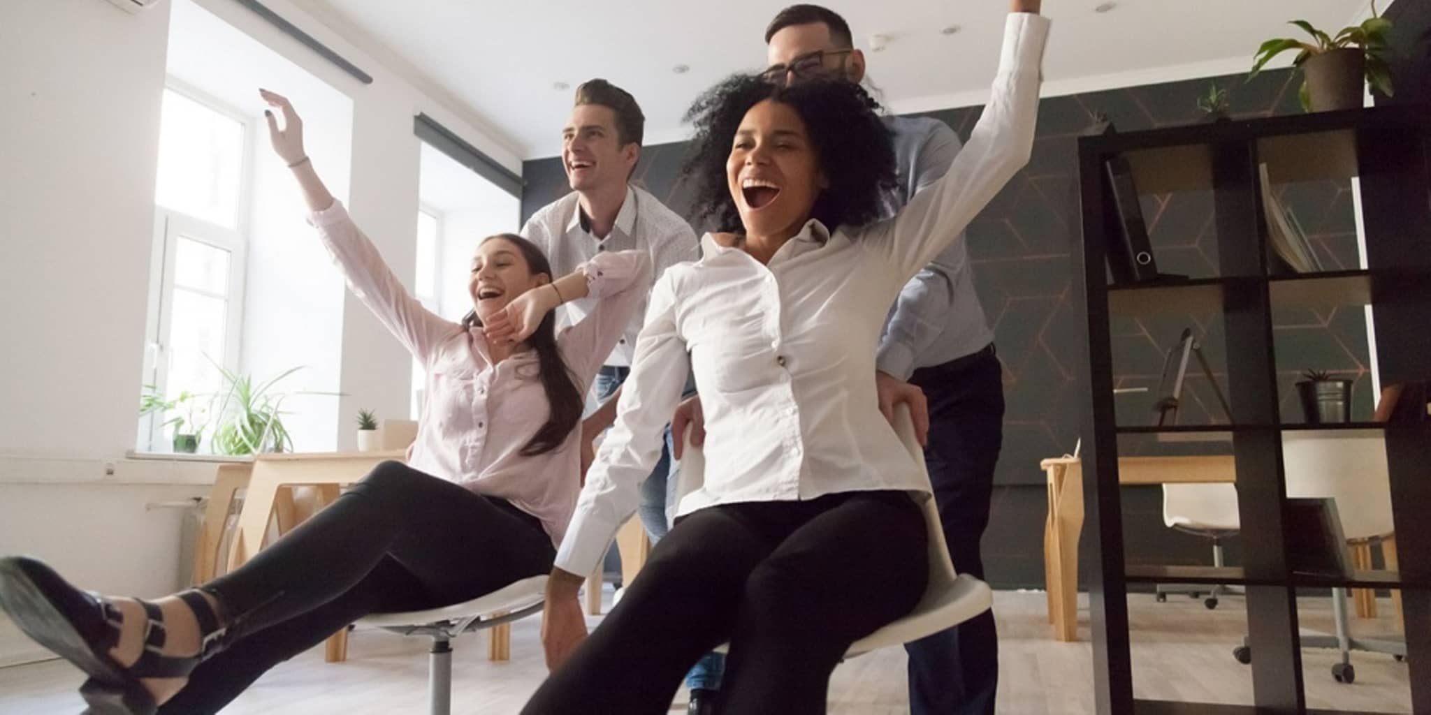 Spaß im Büro: Junge Leute machen Schreibtischstuhl-Wettrennen
