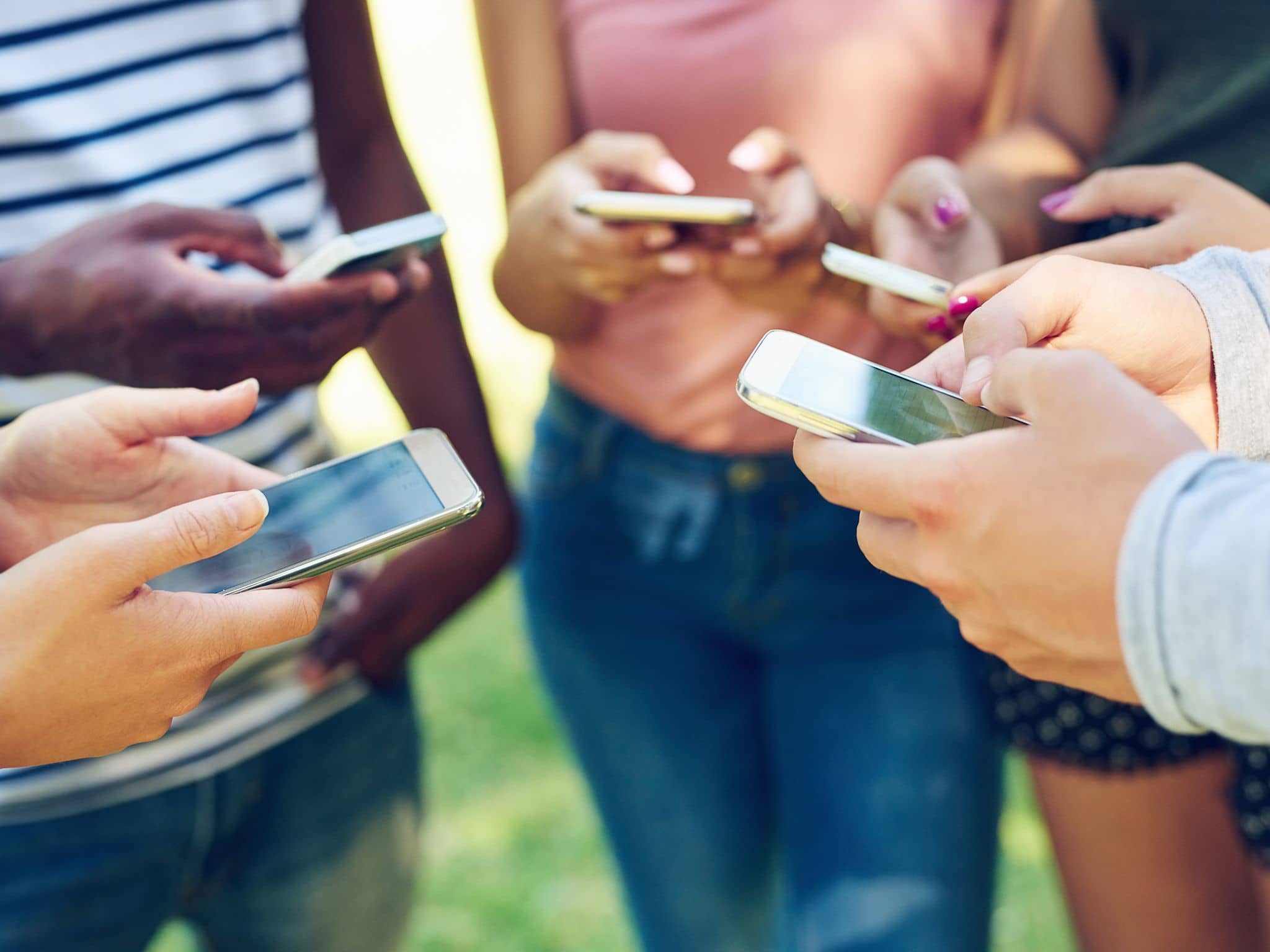 Bild: Eine Gruppe von Jugendlichen steht im Kreis und hält jeweils ein Handy in der Hand.