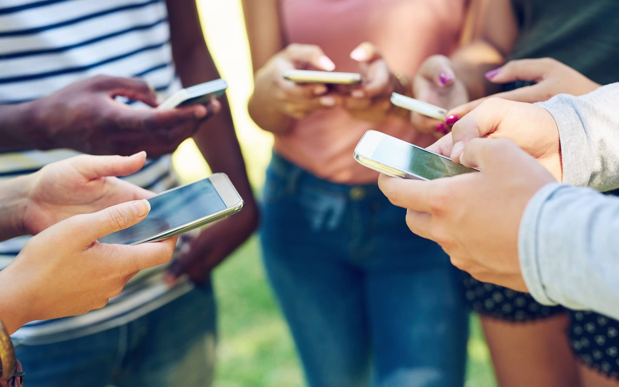 Bild: Eine Gruppe von Jugendlichen steht im Kreis und hält jeweils ein Handy in der Hand.