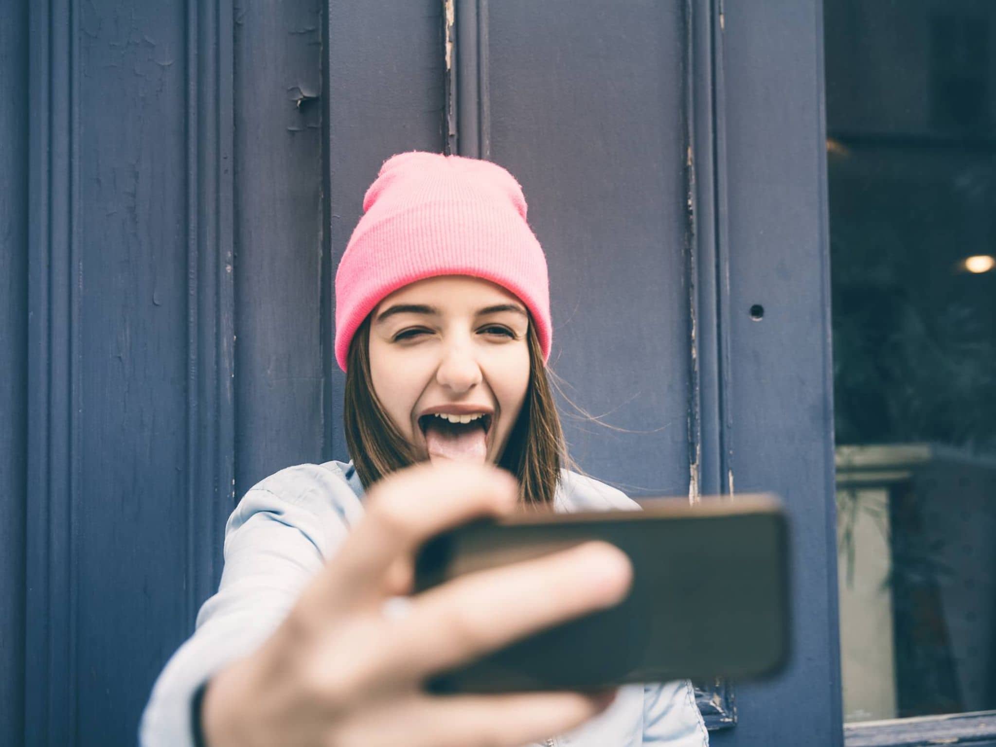 Bild: Jugendliche mit Mütze macht ein Selfie und streckt die Zunge heraus.