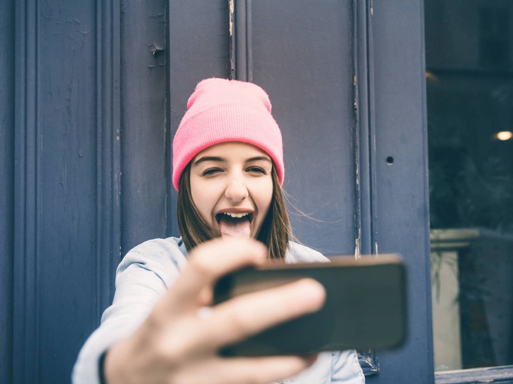 Bild: Jugendliche mit Mütze macht ein Selfie und streckt die Zunge heraus.