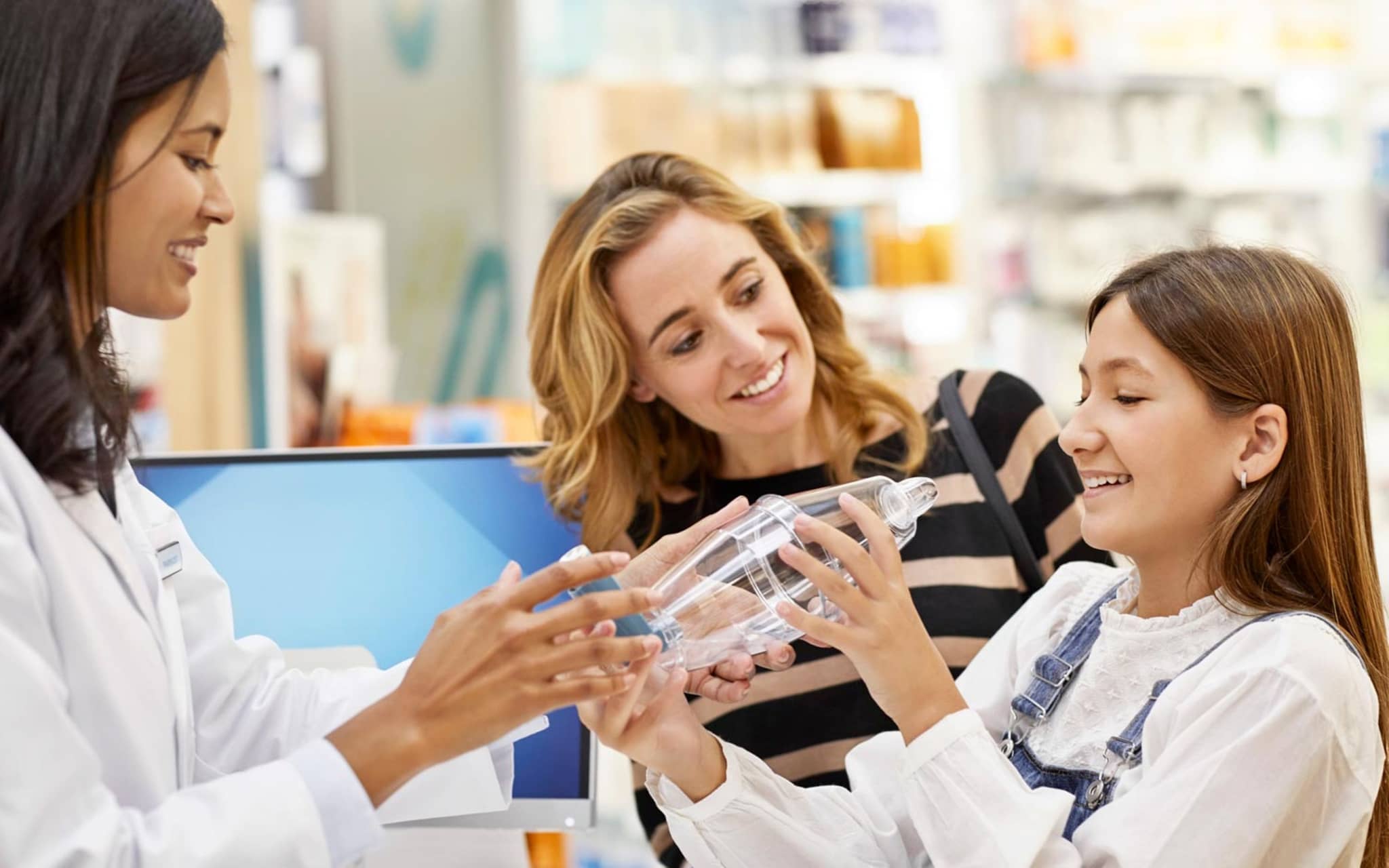 Pharmazeutische Dienstleistungen: Apothekerin erklärt einem Mädchen und seiner Mutter die Handhabung eines Inhalators.