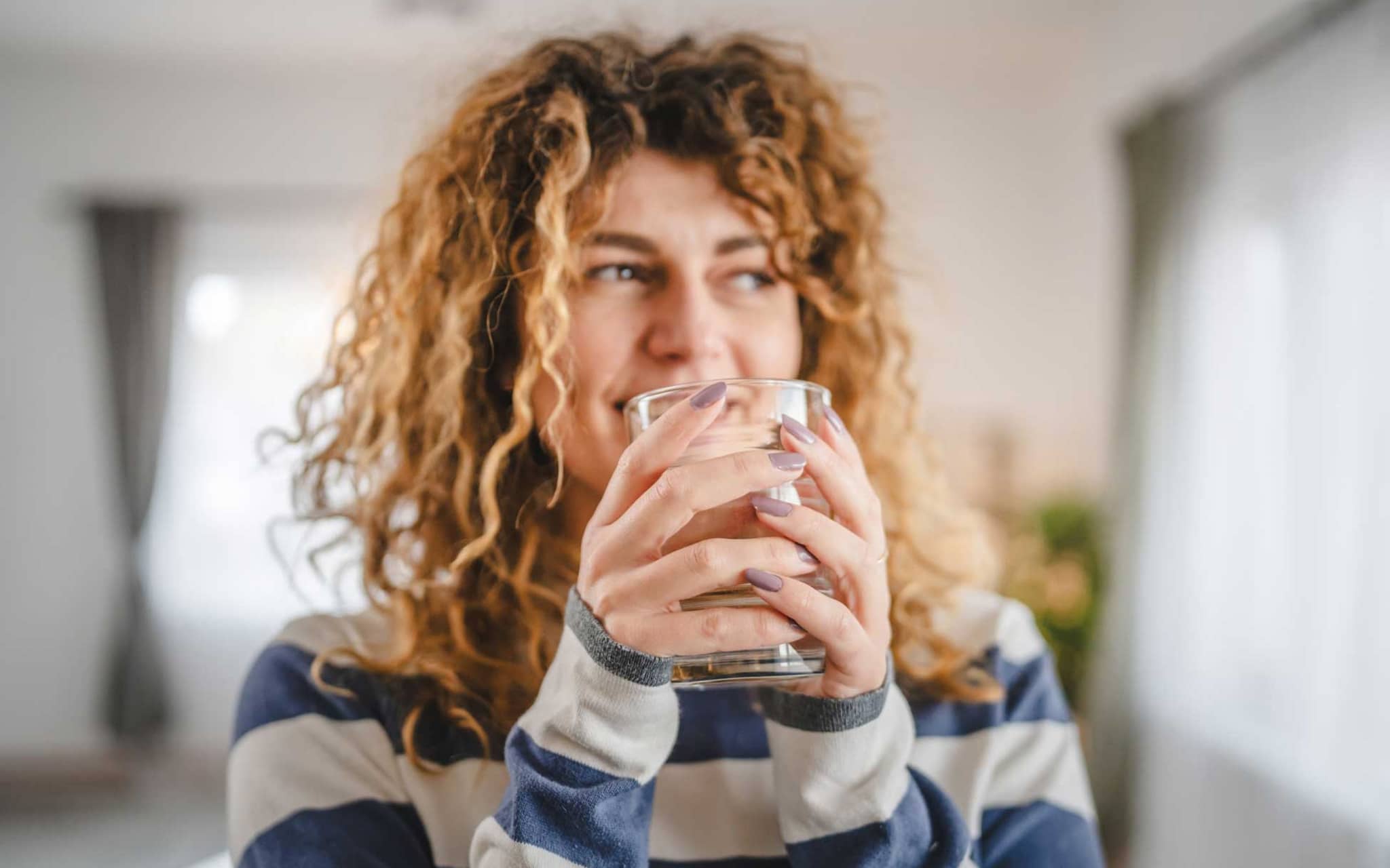 Abnehmen mit Wasser: Junge Frau hält Wasserglas in der Hand