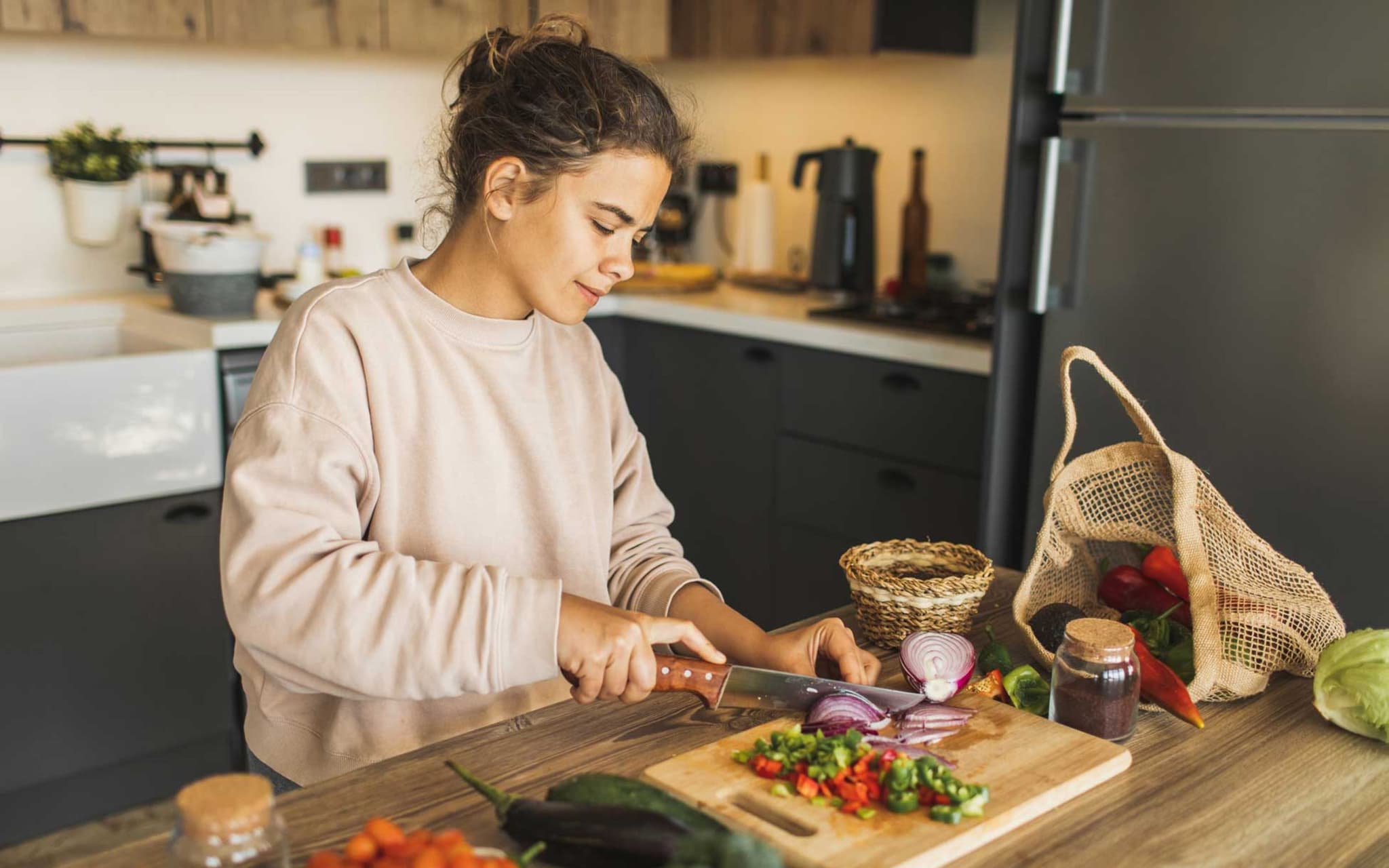 Vegetarische Ernährung: Frau schneidet Gemüse in Küche