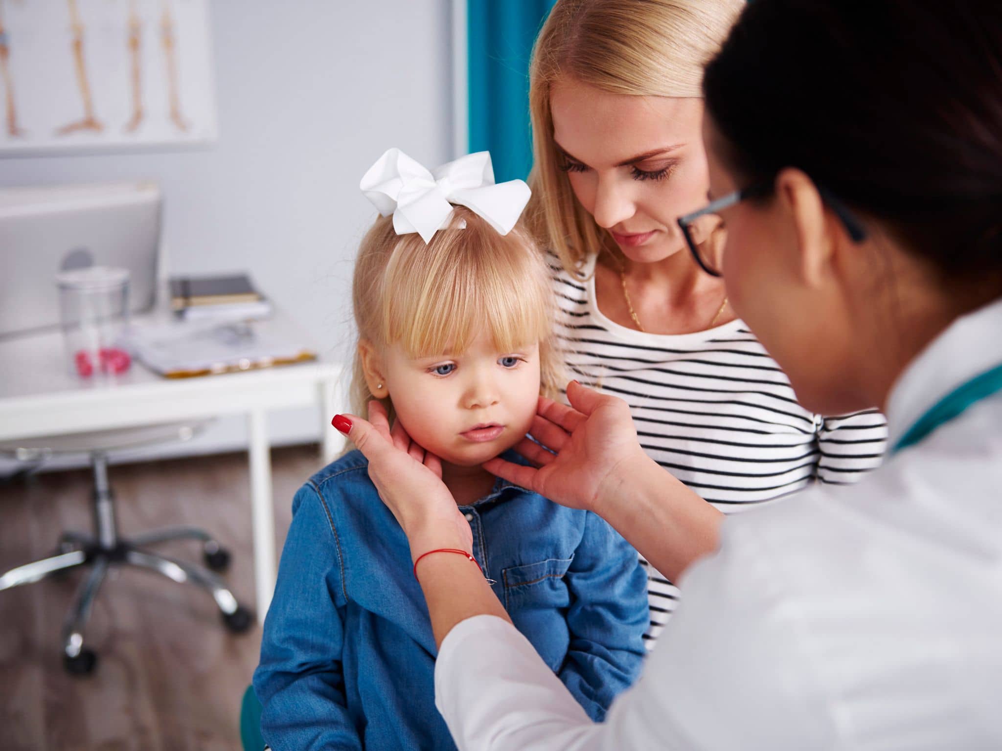 Mandelentzündung: Ärztin tastet die Lymphknoten bei einem kleinen Mädchen ab.