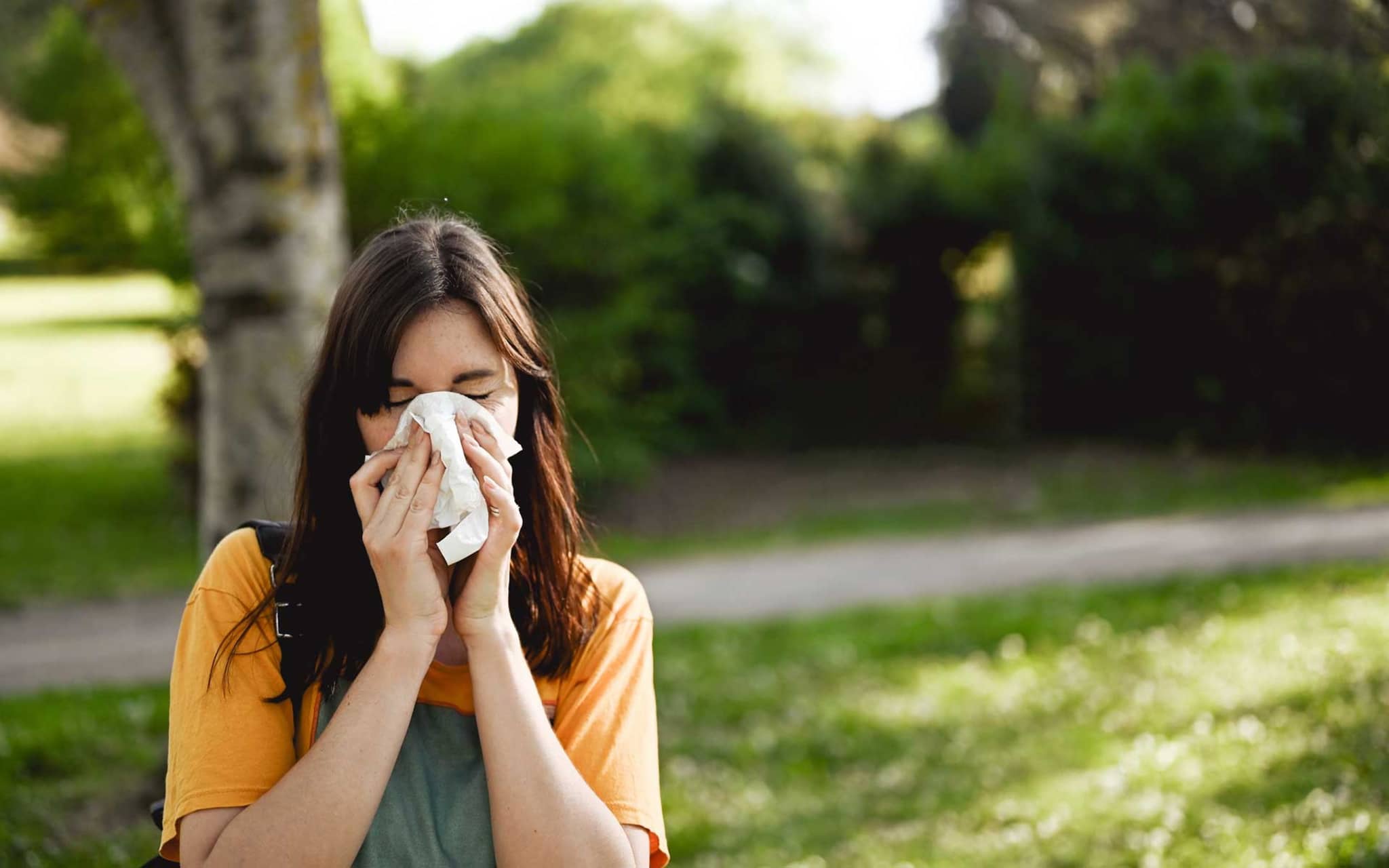 Sommergrippe: Junge Frau putzt sich die Nase