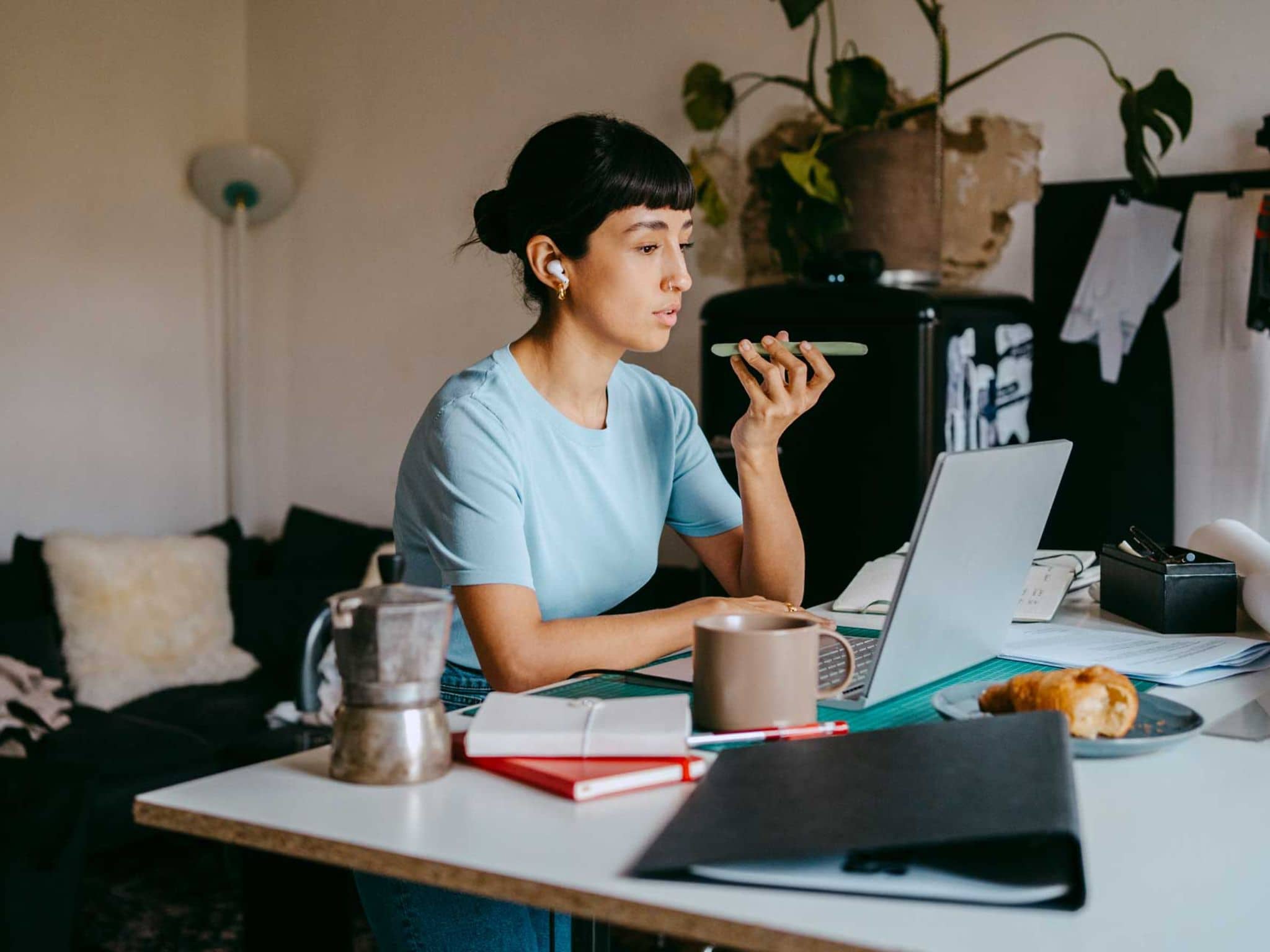 Ständige Erreichbarkeit: Junge Frau im Home Office mit Smartphone und Lapotop