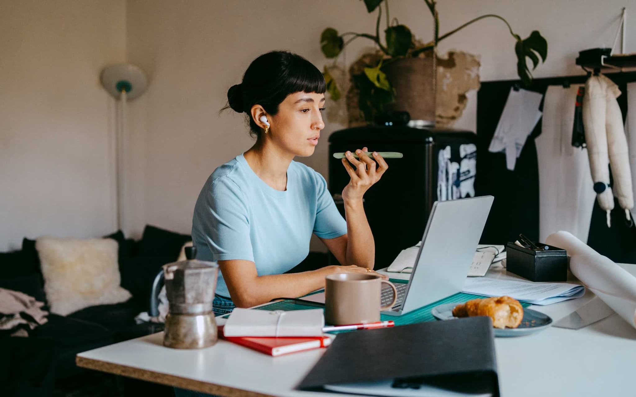 Ständige Erreichbarkeit: Junge Frau im Home Office mit Smartphone und Lapotop