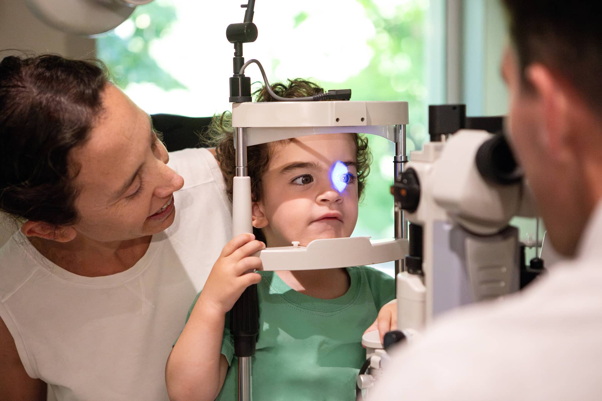 Amblyopiescreening: Kleiner Junge wird beim Augenarzt untersucht, während seine Mutter supportet