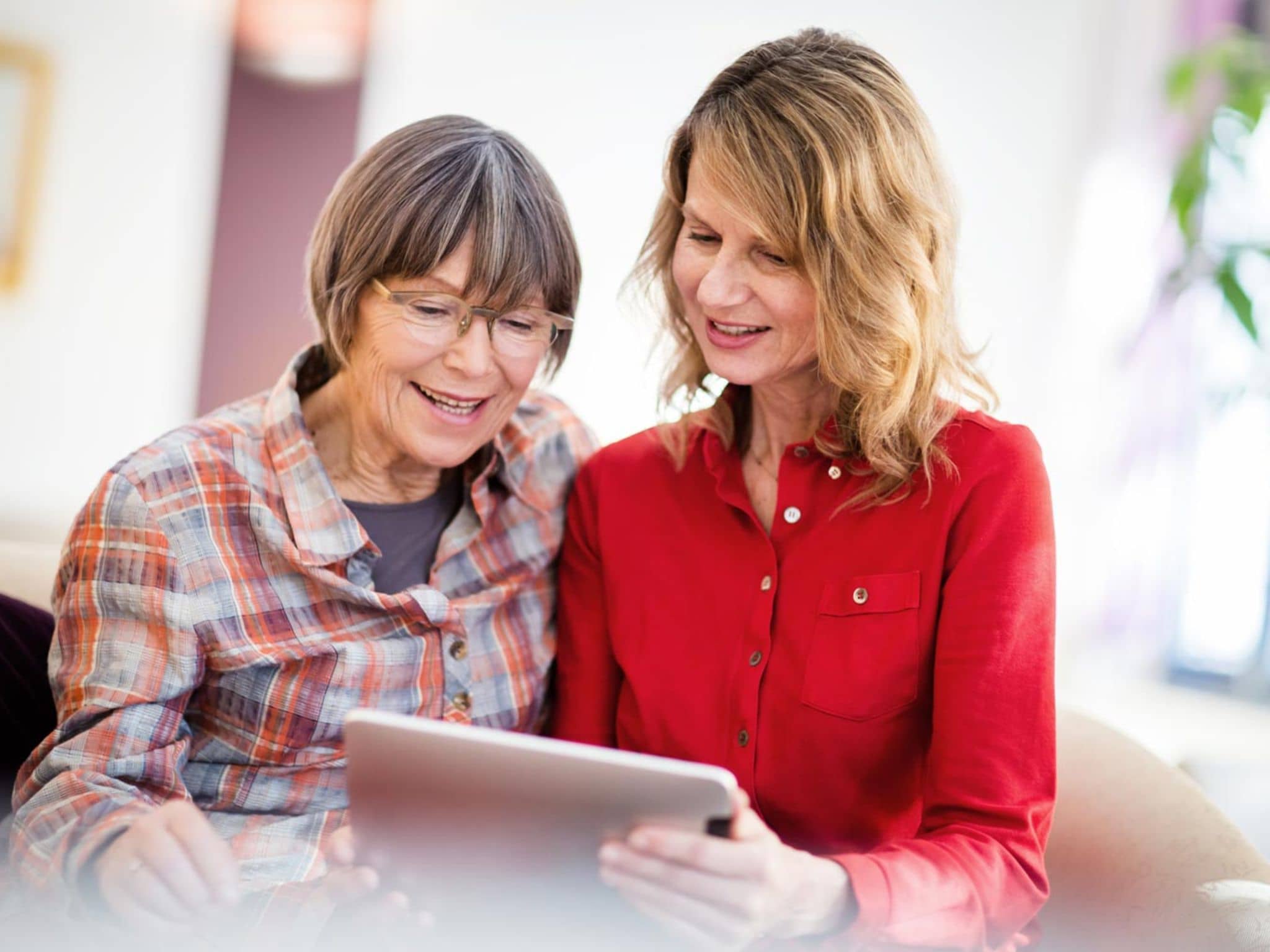 Digitale Pflegeanwendungen (DiPA): Ältere Frau und ihre Tochter schauen gemeinsam auf ein digitales Tablet.