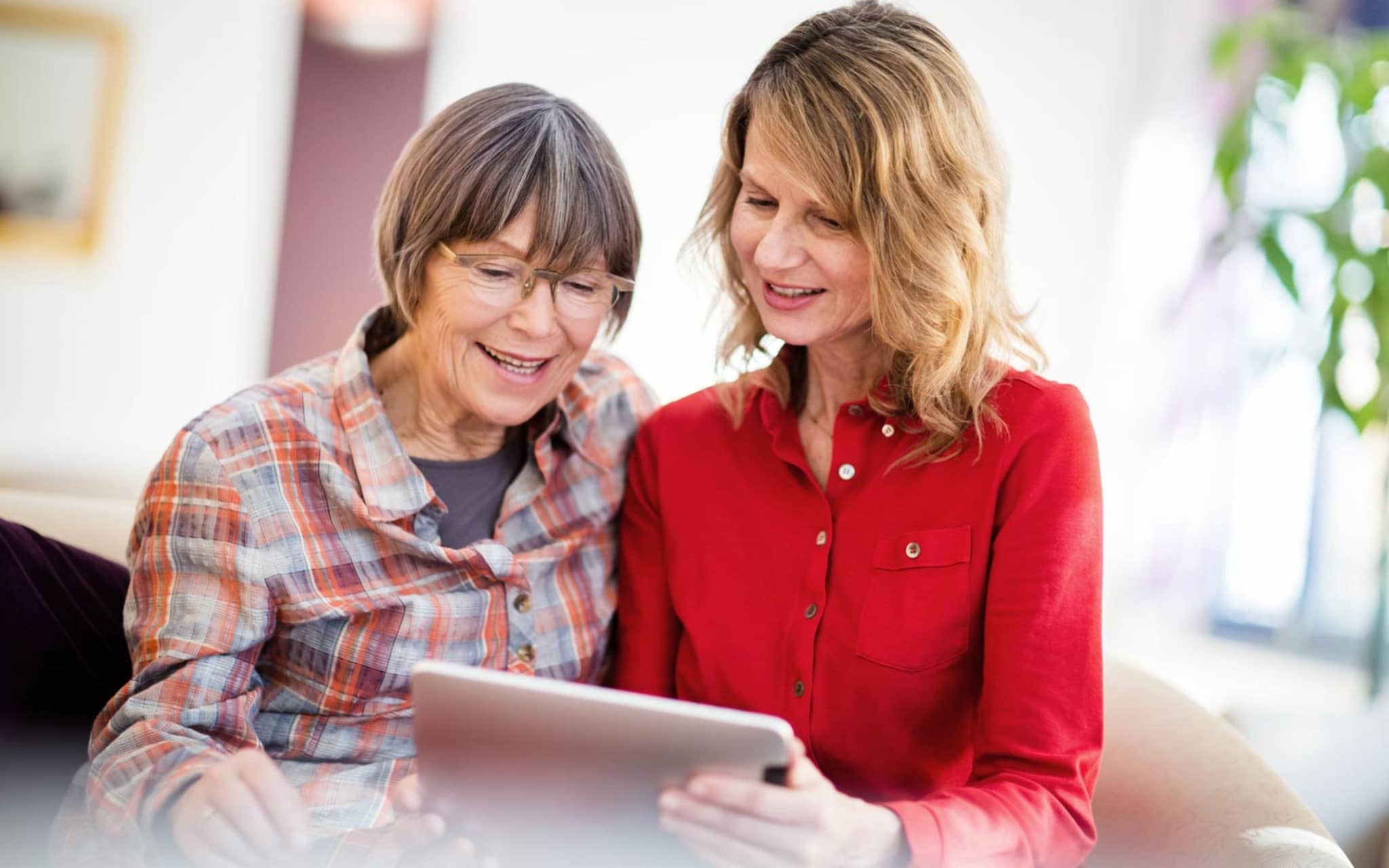 Digitale Pflegeanwendungen (DiPA): Ältere Frau und ihre Tochter schauen gemeinsam auf ein digitales Tablet.