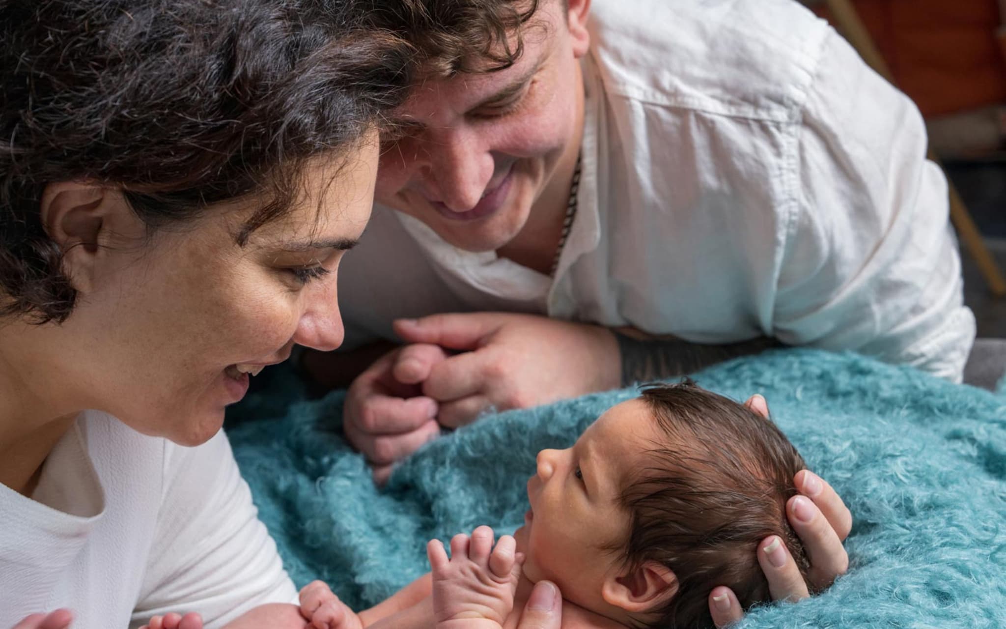 Geburtshilfe: Ein glückliches Paar schaut nach der Geburt zärtlich auf das Baby.