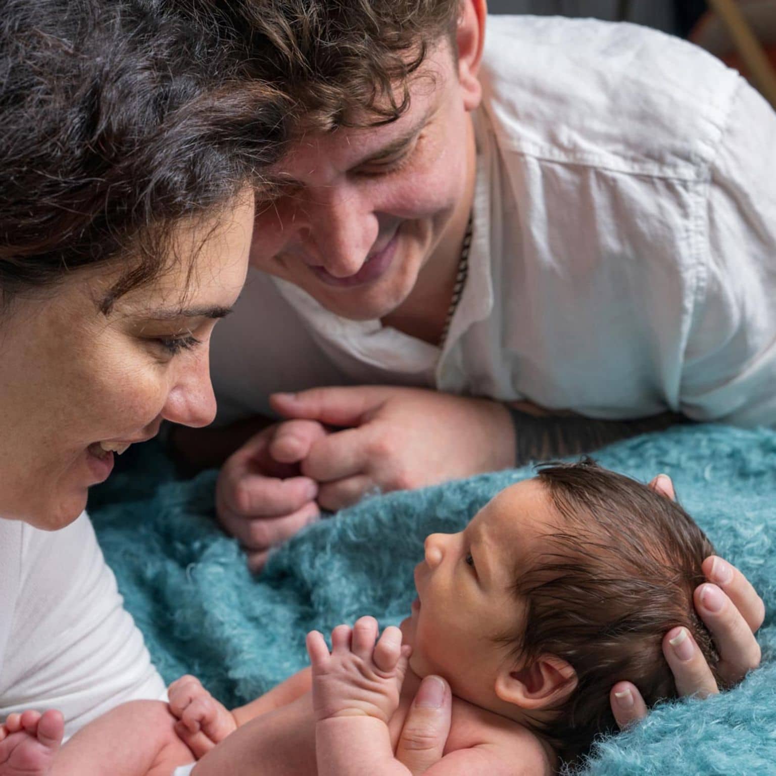 Geburtshilfe: Ein glückliches Paar schaut nach der Geburt zärtlich auf das Baby.