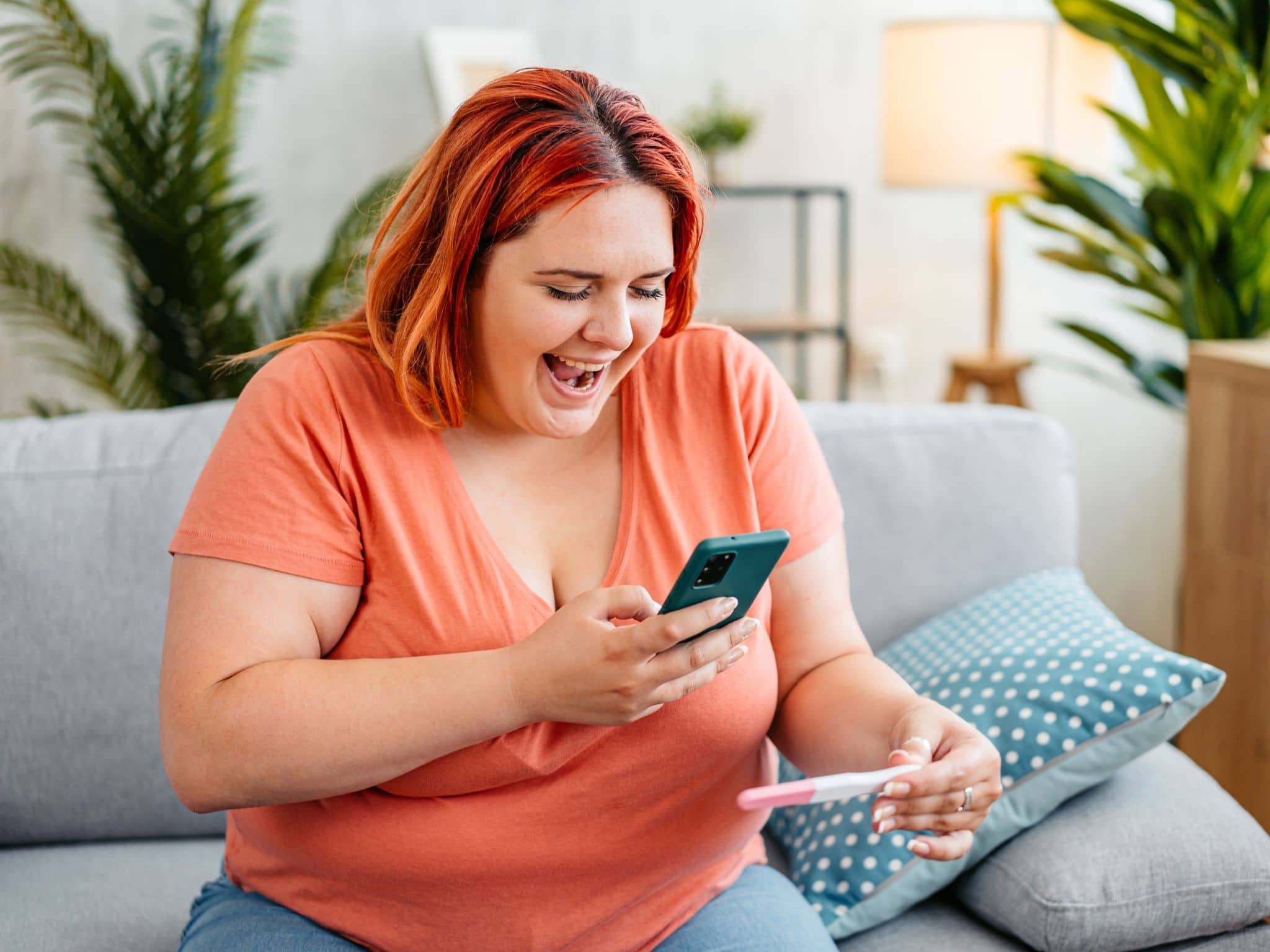 Schwanger werden mit Adipositas: Eine übergewichtige Frau hält einen positiven Schwangerschaftstest in der Hand