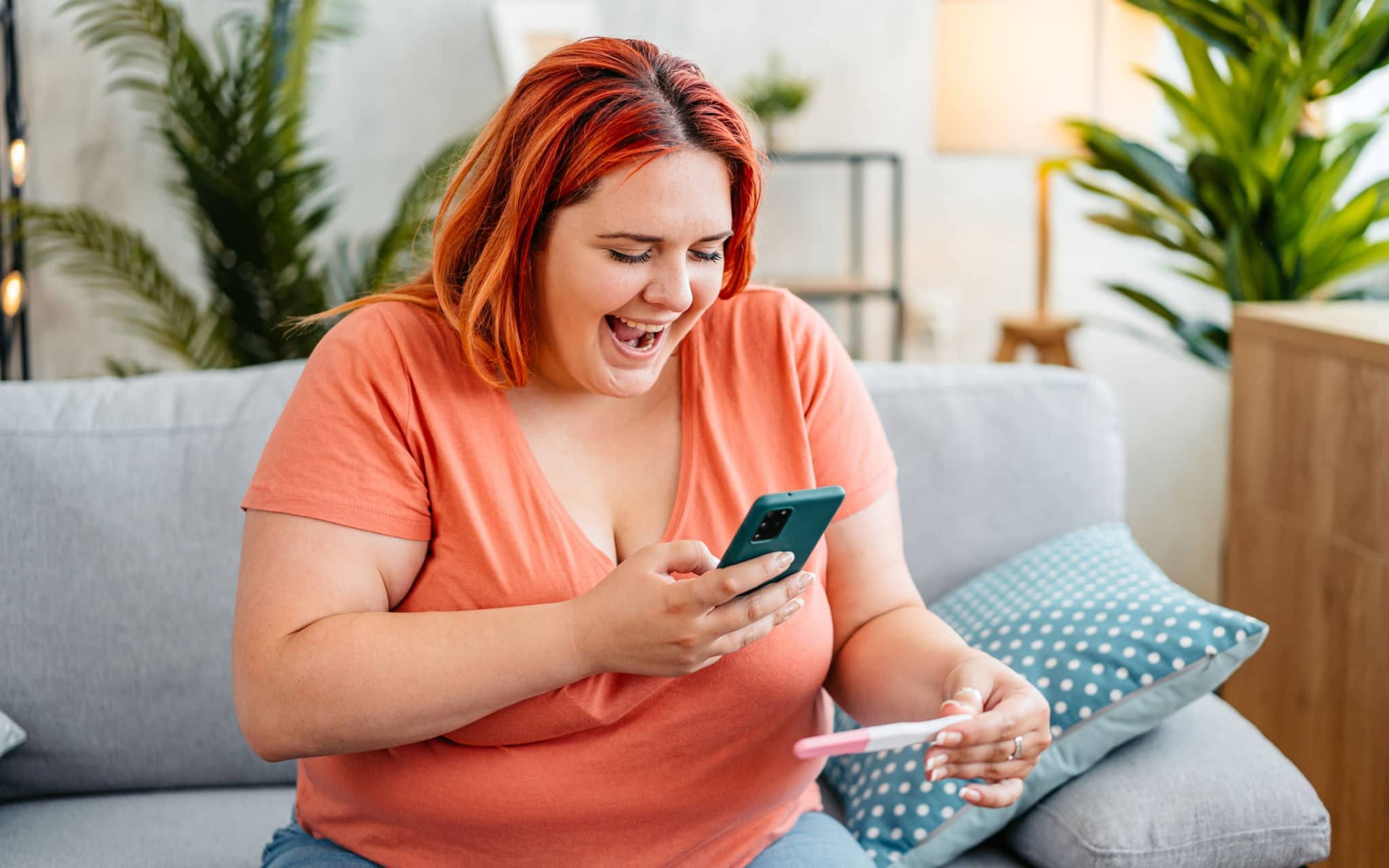 Schwanger werden mit Adipositas: Eine übergewichtige Frau hält einen positiven Schwangerschaftstest in der Hand