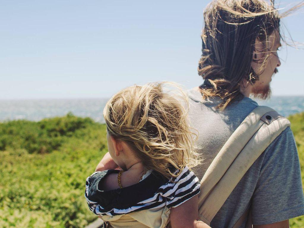 Reiseimpfung: Mann trägt Kind auf dem Rücken in der Natur