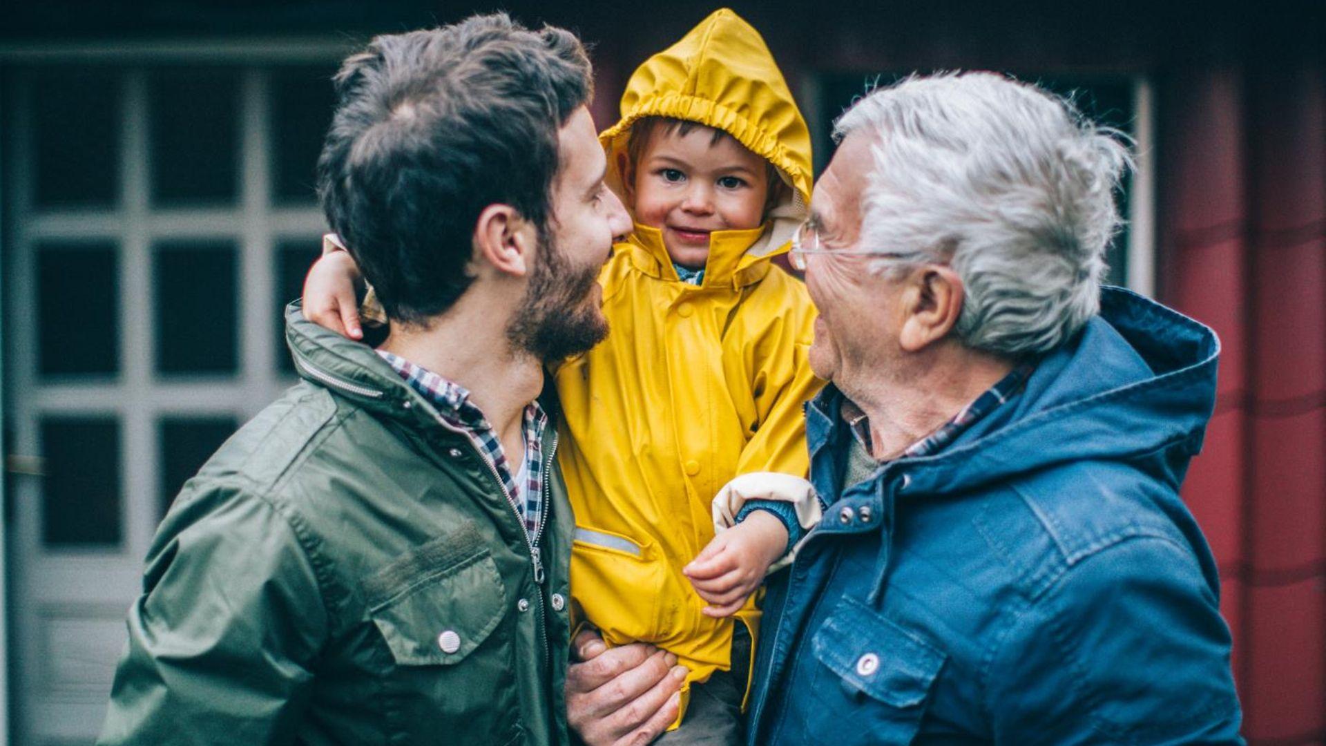 Großvater und Vater halten gemeinsam einen Jungen auf dem Arm